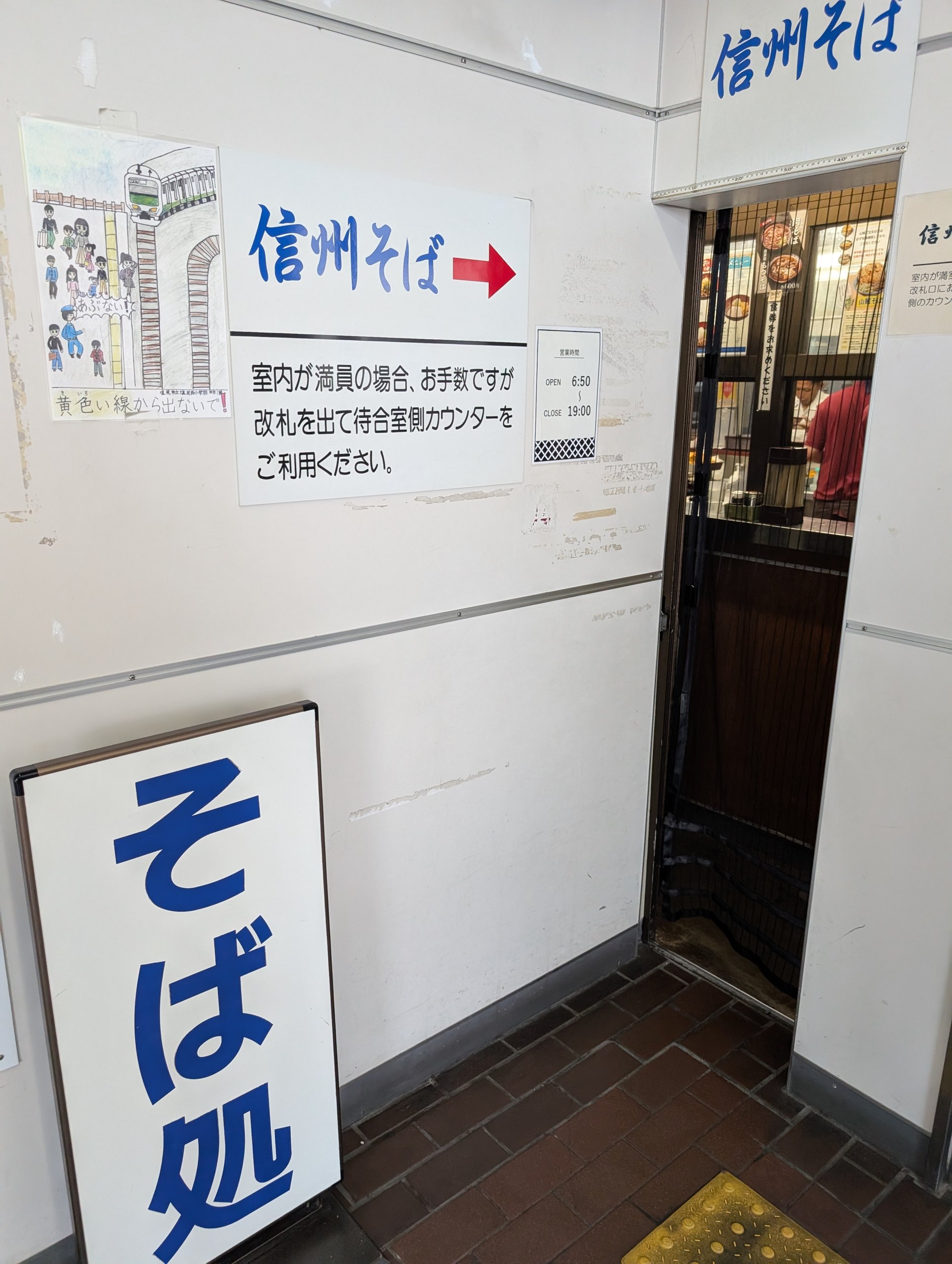 「信州そば」の看板と「そば処」の看板がある、せまい入口