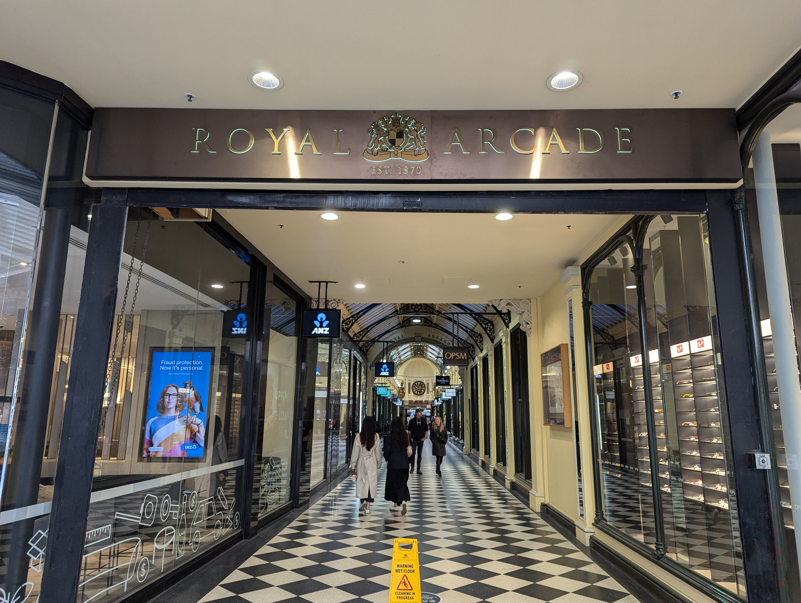 「ROYAL ARCADE」の文字の下、白黒の市松模様の床が奥へ続くアーケード
