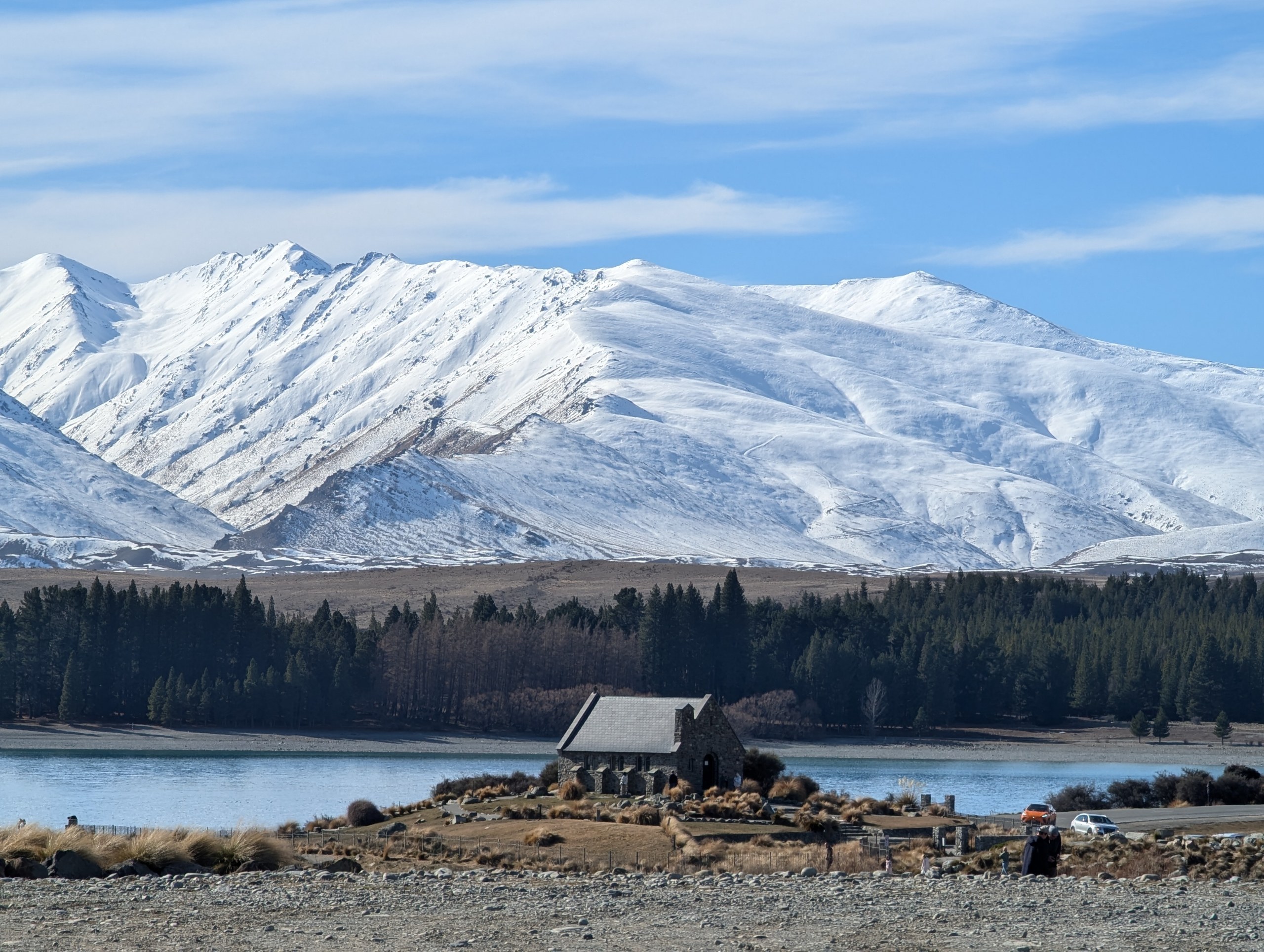 雪をかぶった山と森を背に、テカポ湖のほとりに建つ小さな石の教会