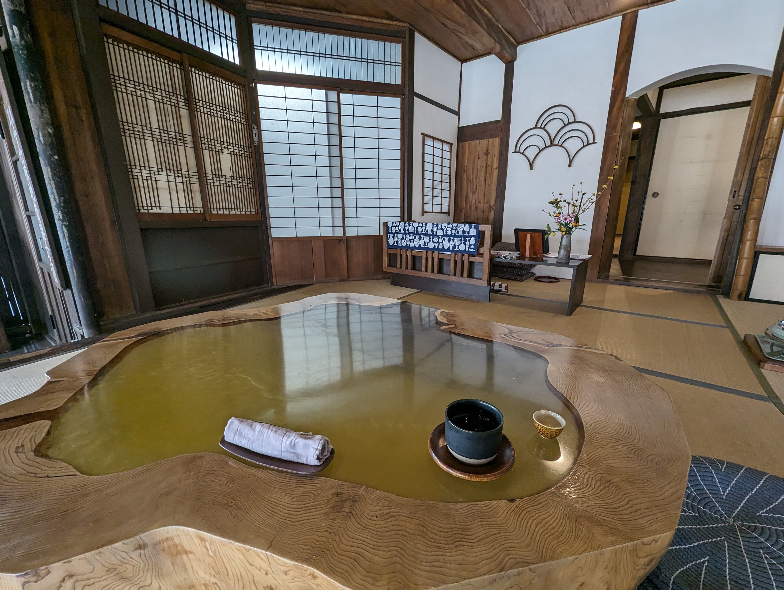 一枚板の大きなテーブルに、お茶とおしぼりが置かれた和室