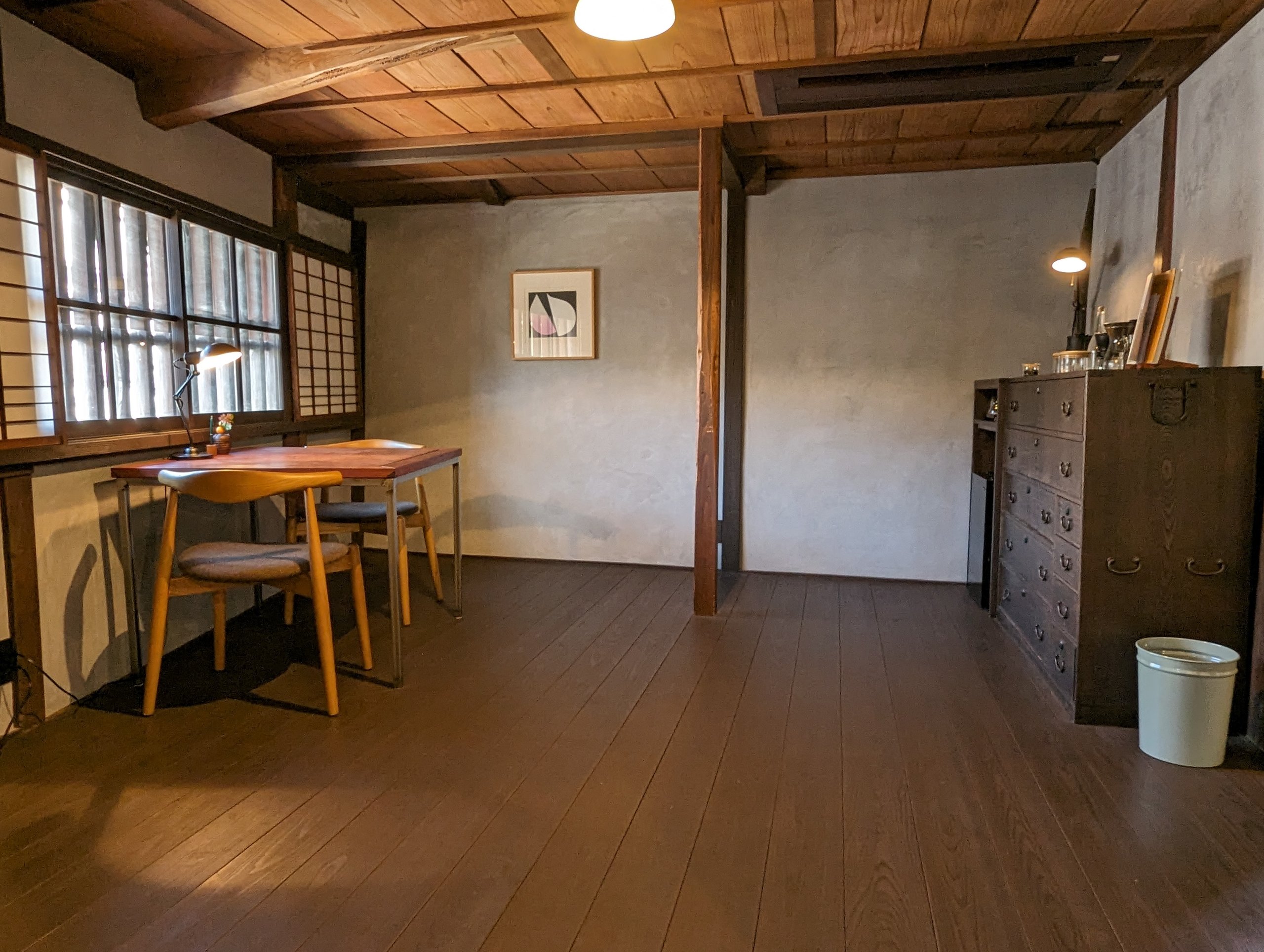 窓辺に机と椅子が置かれた、板張りの部屋