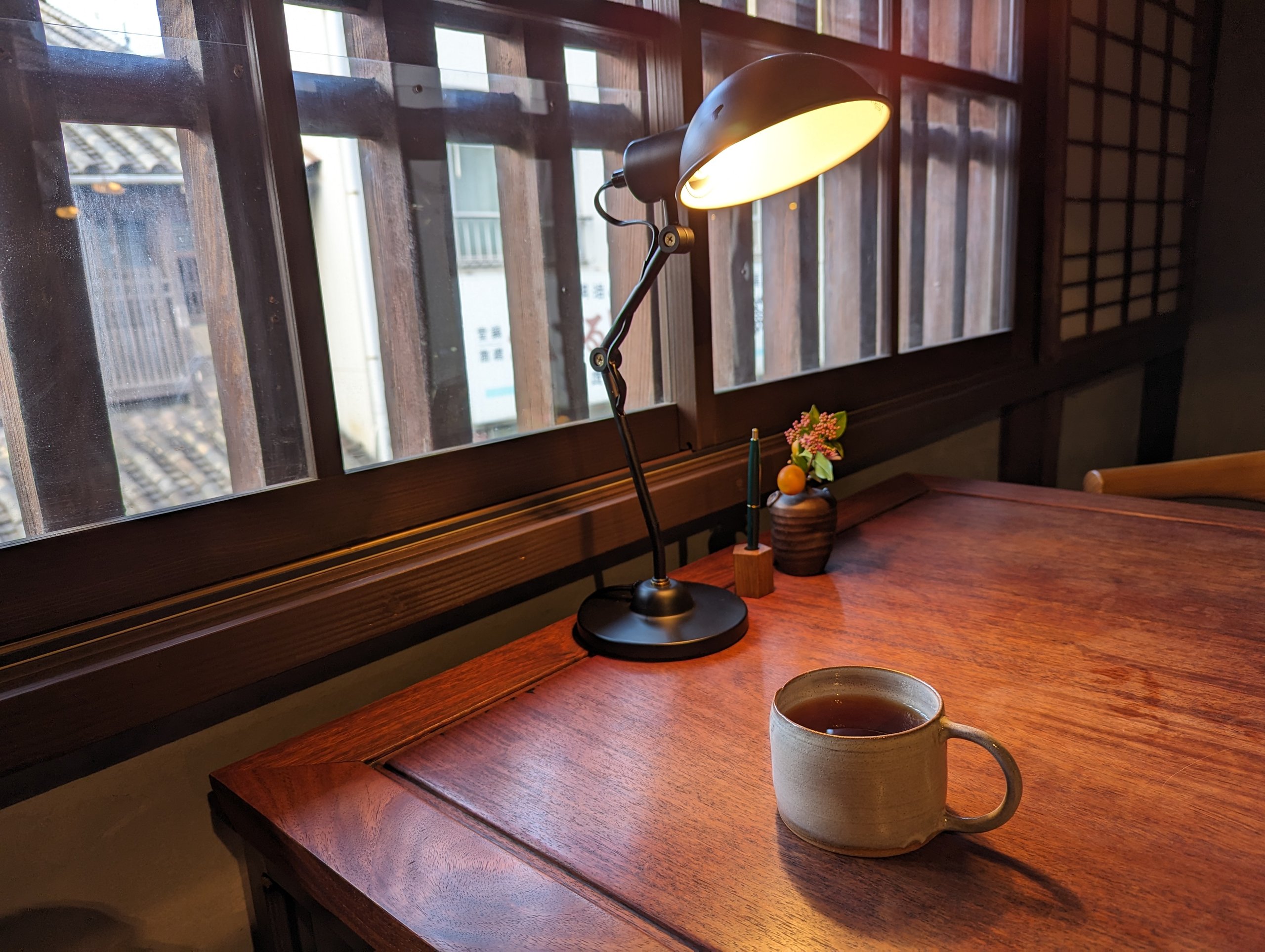 格子窓のそばの机に、ランプとお茶のカップ