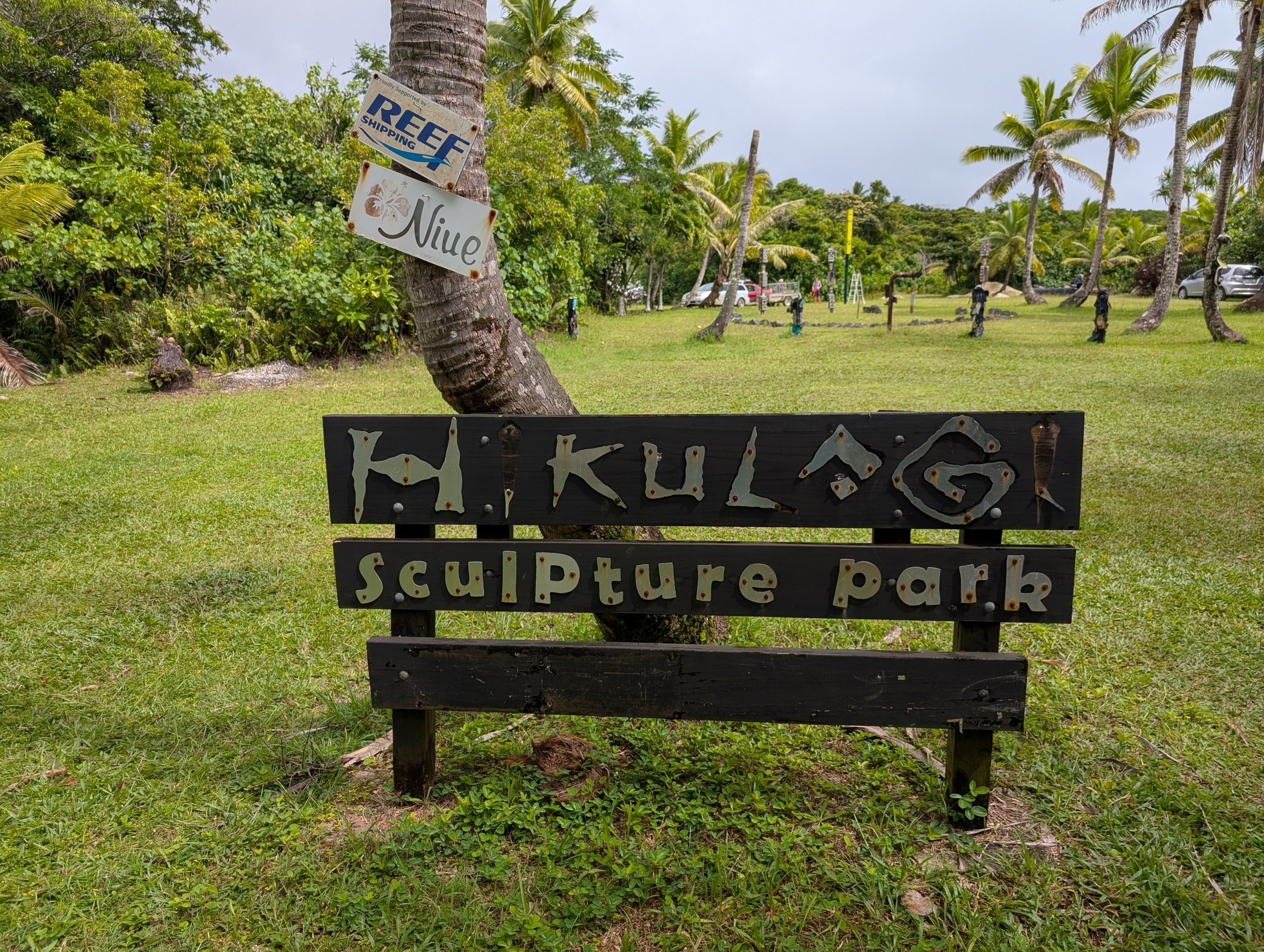 「Hikulagi Sculpture park」の木の看板と、芝生の公園