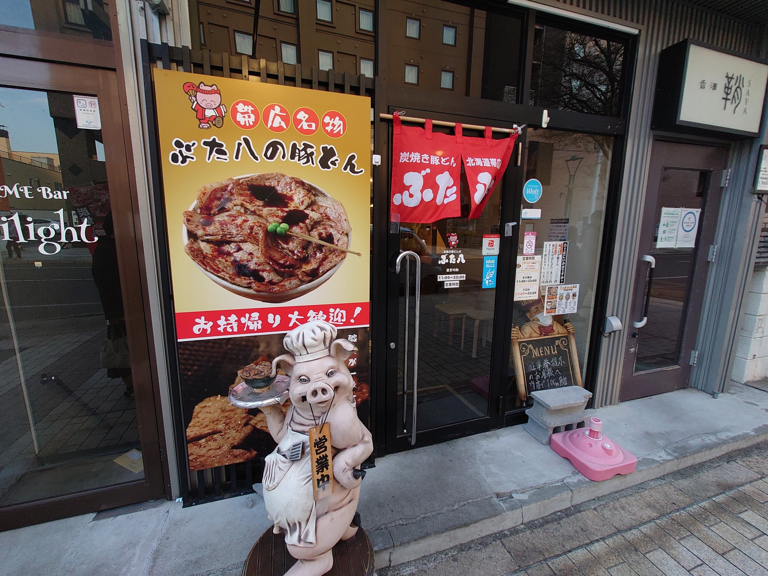 豚のキャラクターの人形と豚丼の看板が立つ「ぶた八」の店先