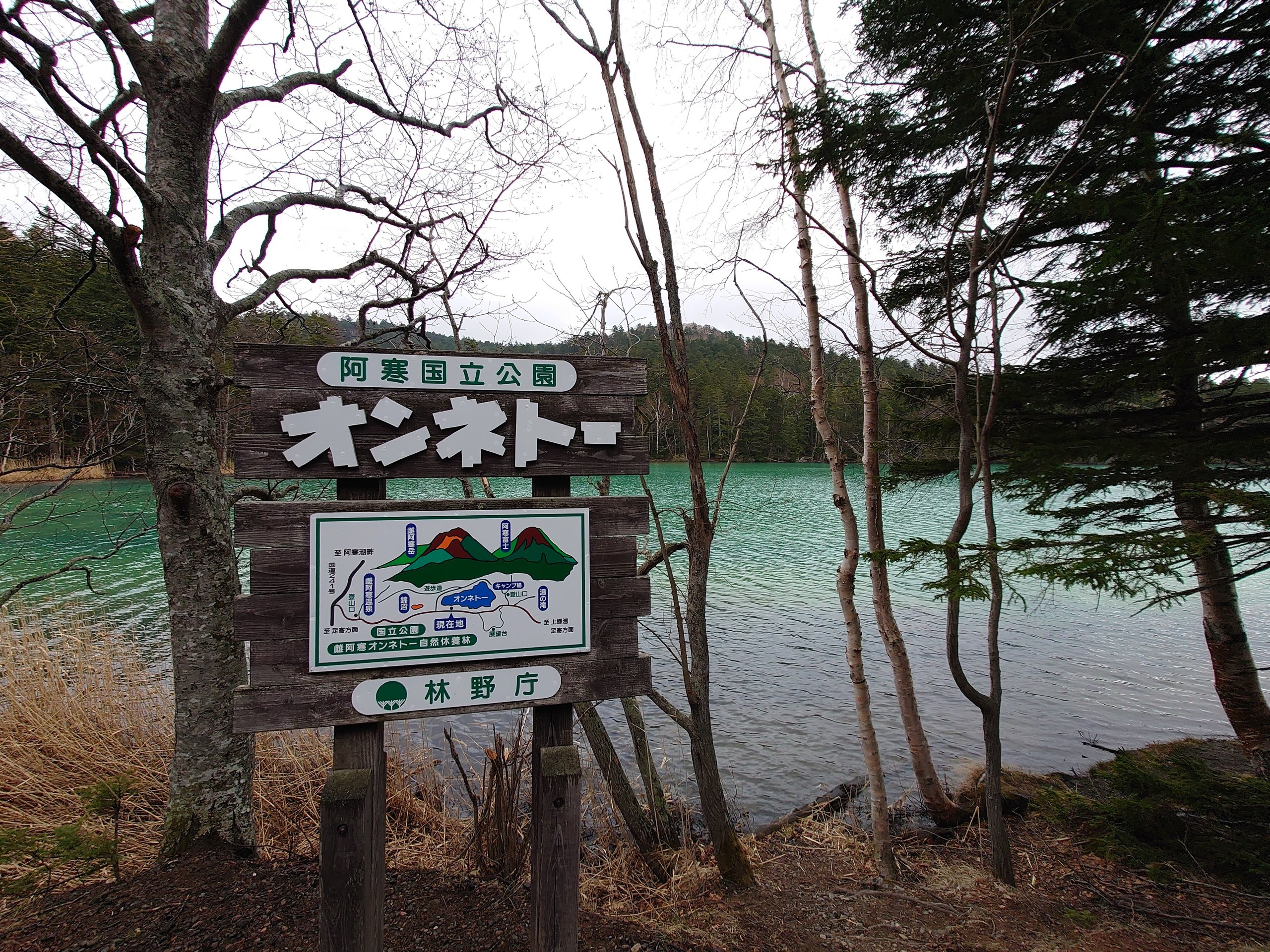 「オンネトー」の看板と、木々の間に見えるエメラルドグリーンの湖面