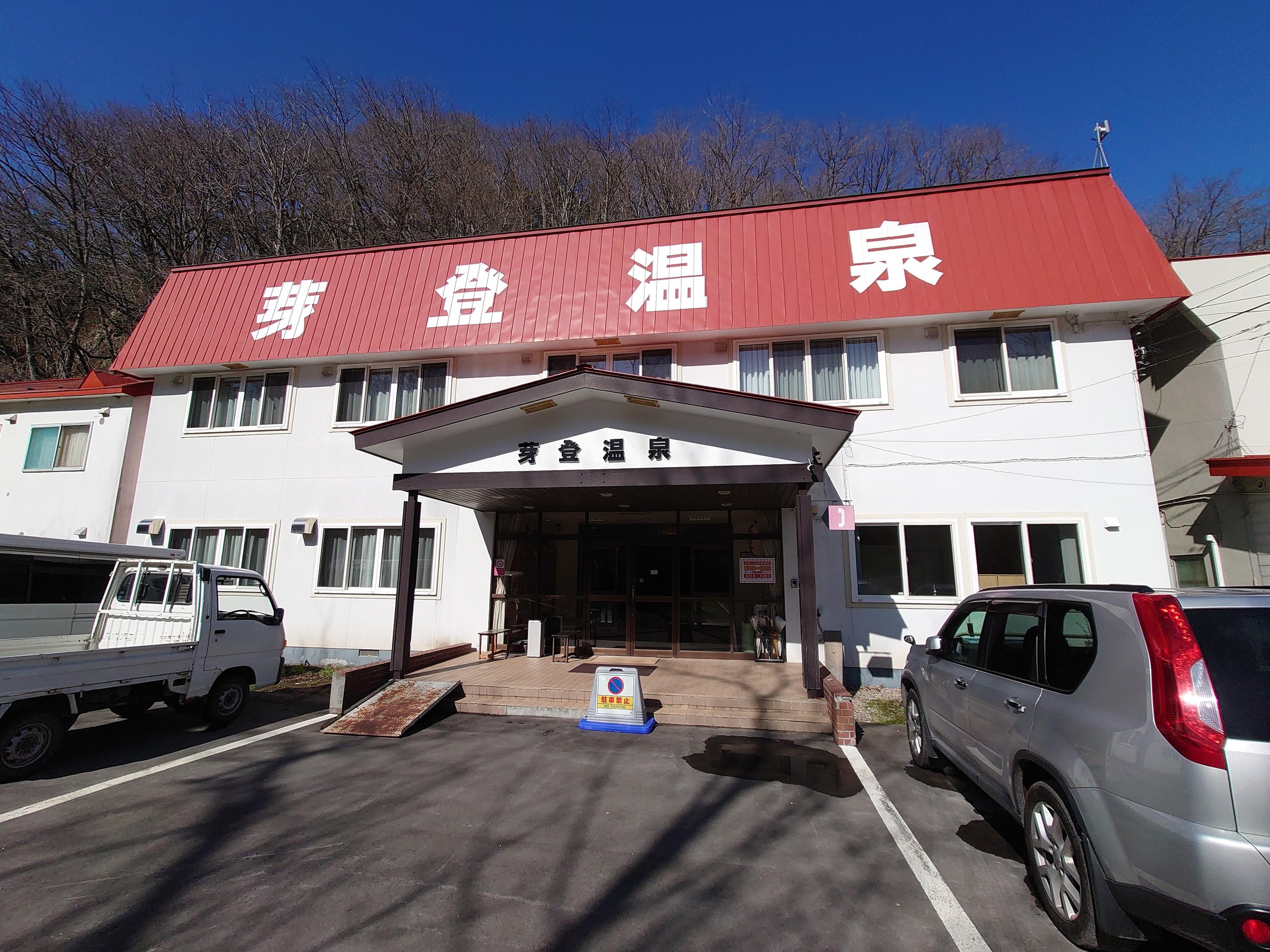 赤い屋根に「芽登温泉」の文字が掲げられた建物