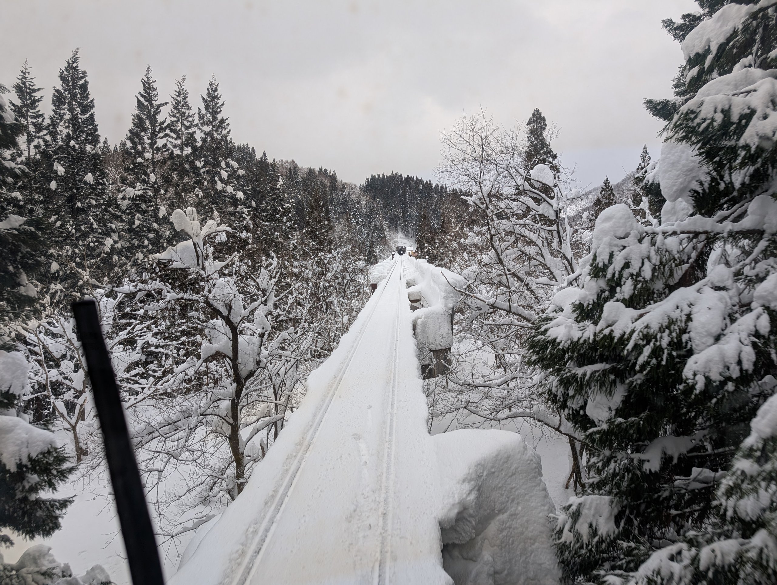 運転席の窓から見た、雪をかぶった鉄橋と、その先の山
