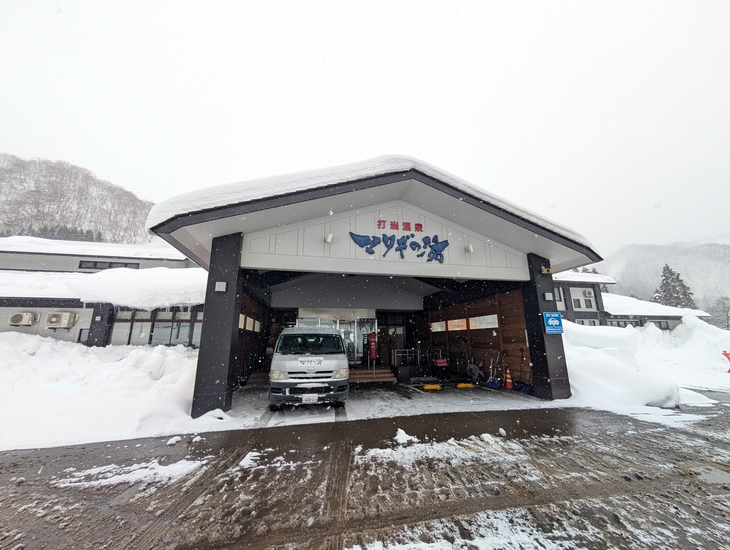 雪の中に建つ、「打当温泉 マタギの湯」の看板がかかった建物