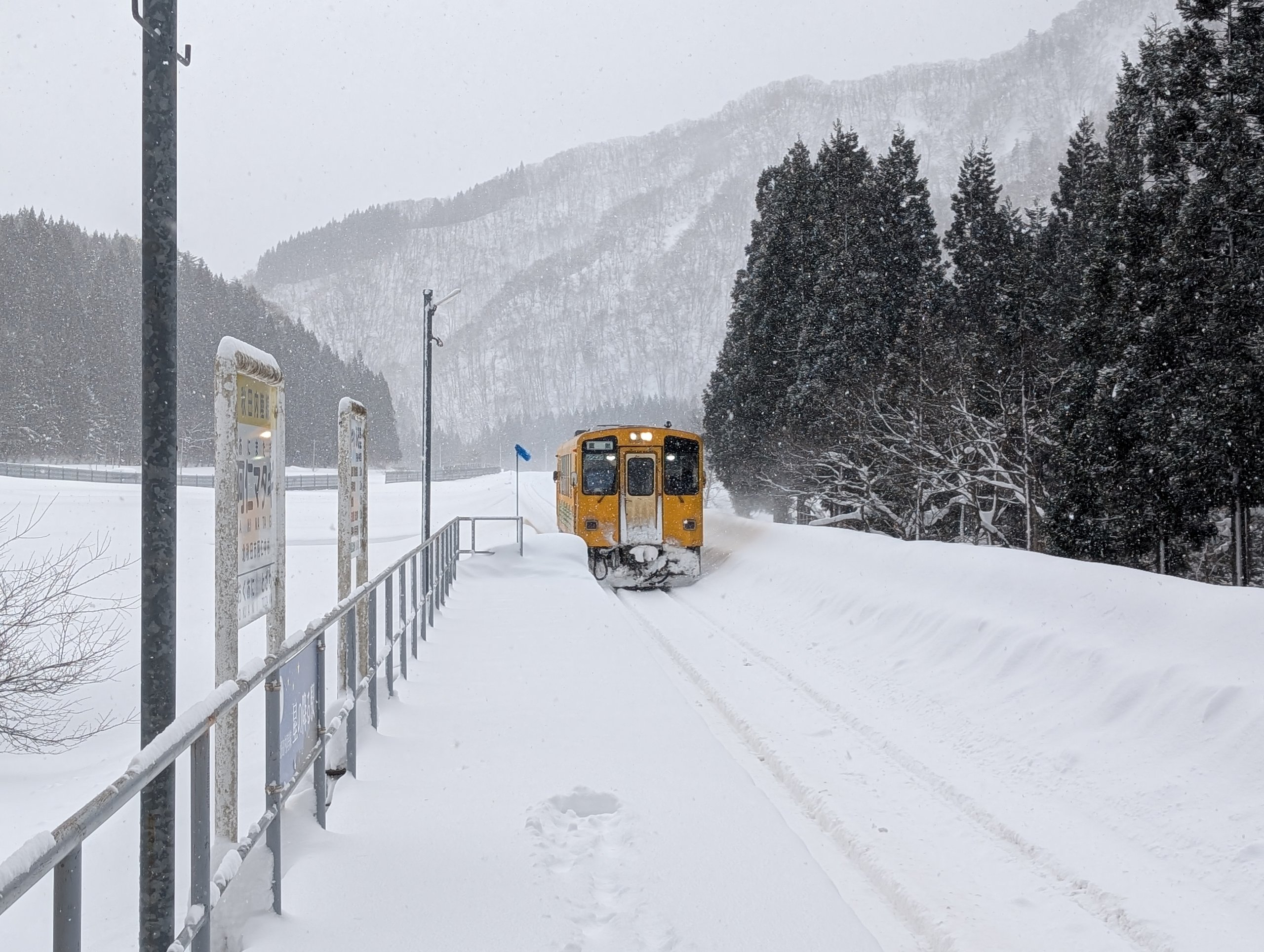 雪の積もったホームに、雪をかき分けて入ってくる黄色い列車