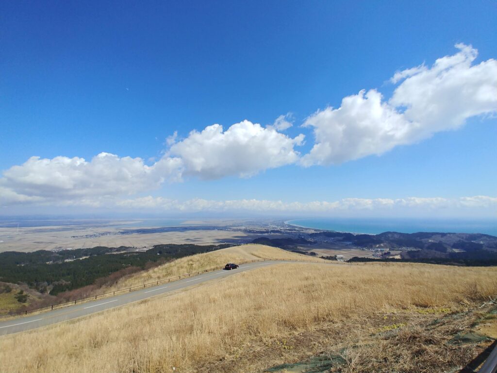 寒風山から見下ろす、枯れ草色の山肌と広い平野、海岸線