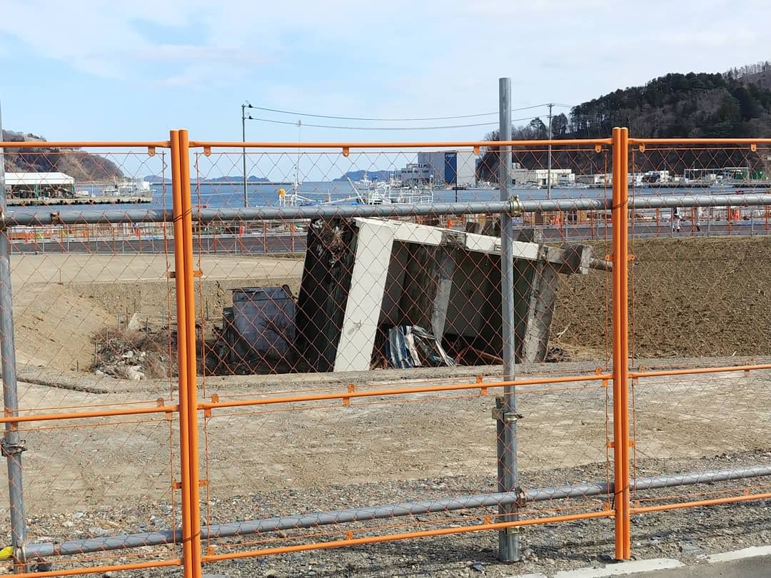 フェンスの向こうに残る、津波で倒れた建物