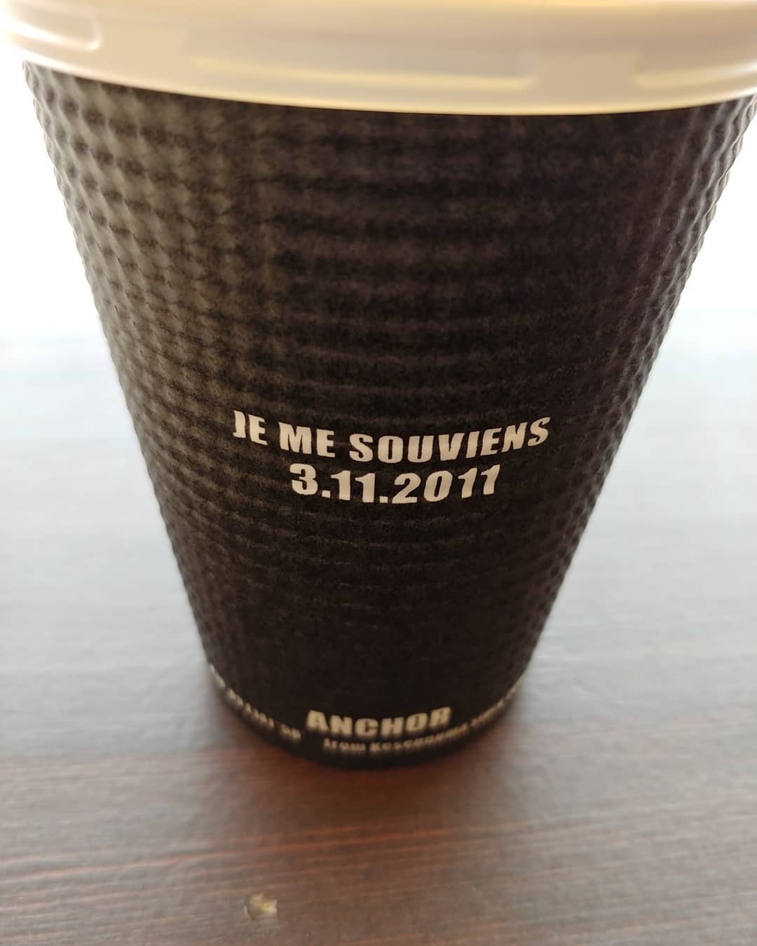 「JE ME SOUVIENS 3.11.2011」と書かれたコーヒーのカップ