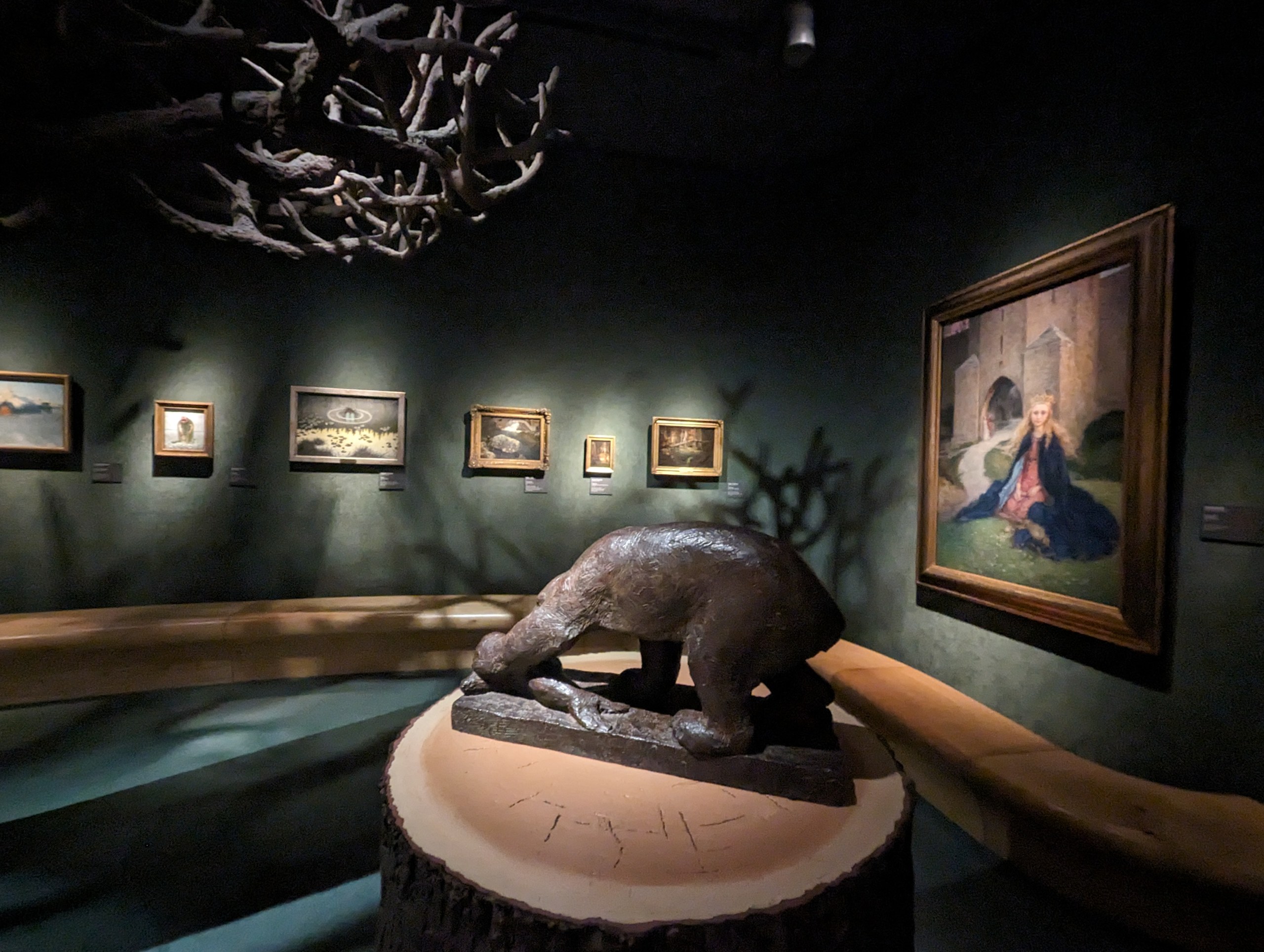熊の彫刻と、壁に並ぶ絵画の展示室