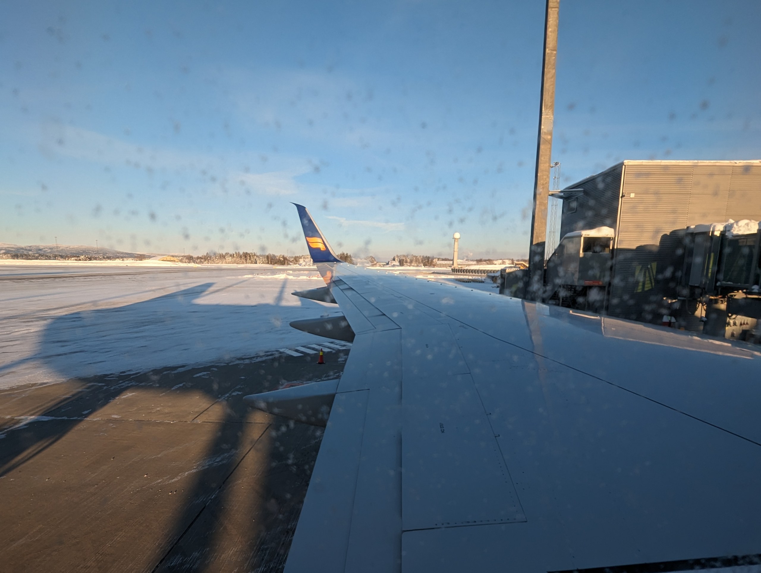 機内の窓から見た、雪の空港と飛行機の翼