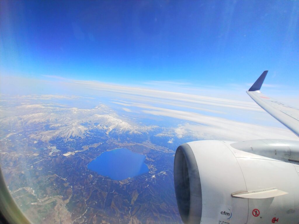 飛行機の窓から見えた雪の山と十和田湖
