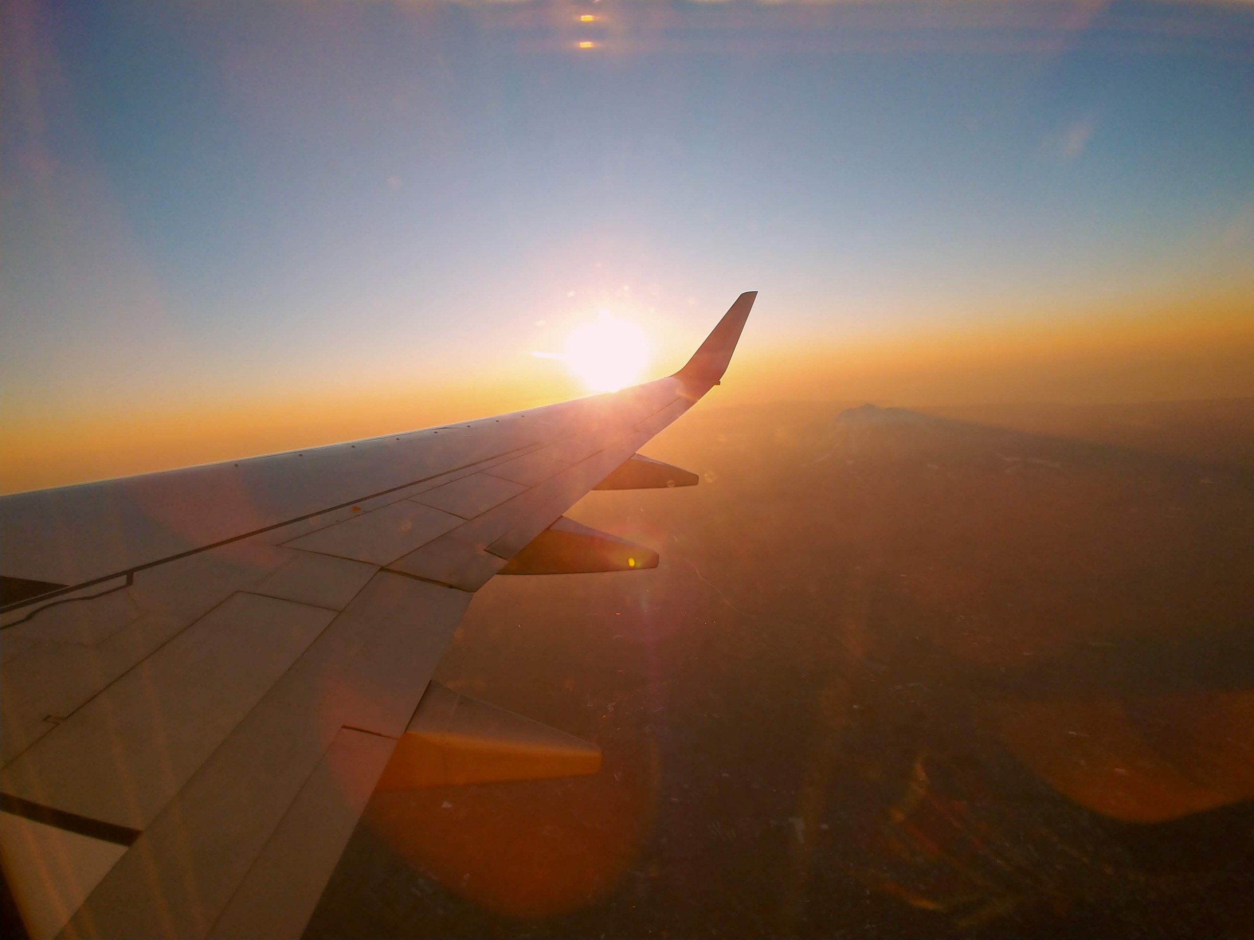 飛行機の窓から見た夕焼けと翼