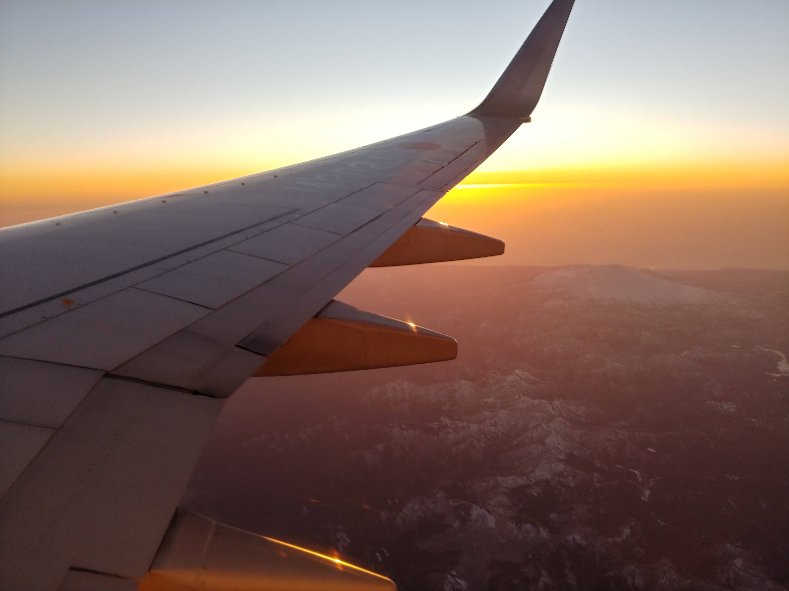 夕日に染まる雲と飛行機の翼