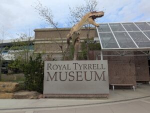 「ROYAL TYRRELL MUSEUM」の看板と、建物の前で口を開けたティラノサウルスの像