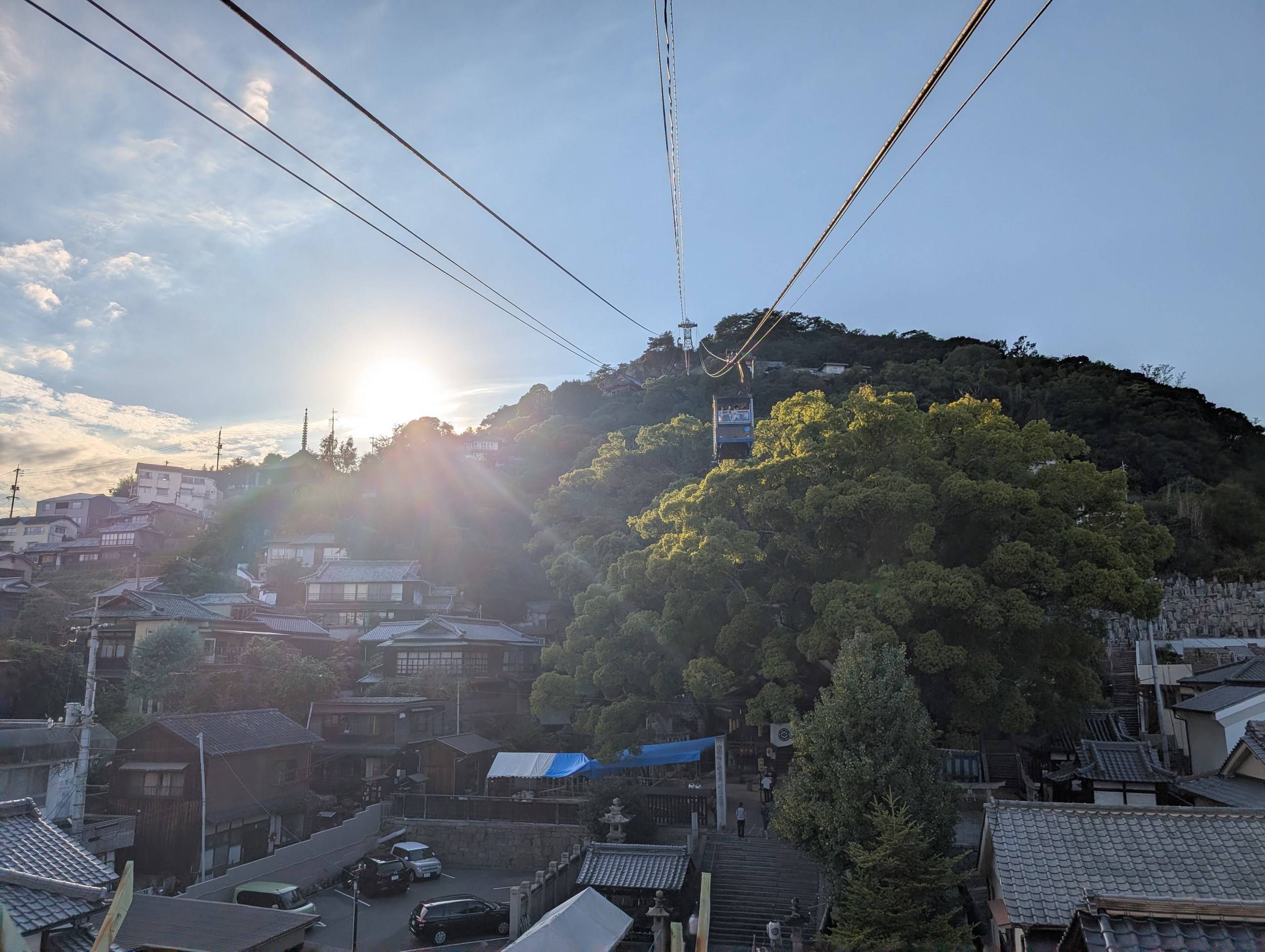 ロープウェイのケーブルと、山の向こうの夕日