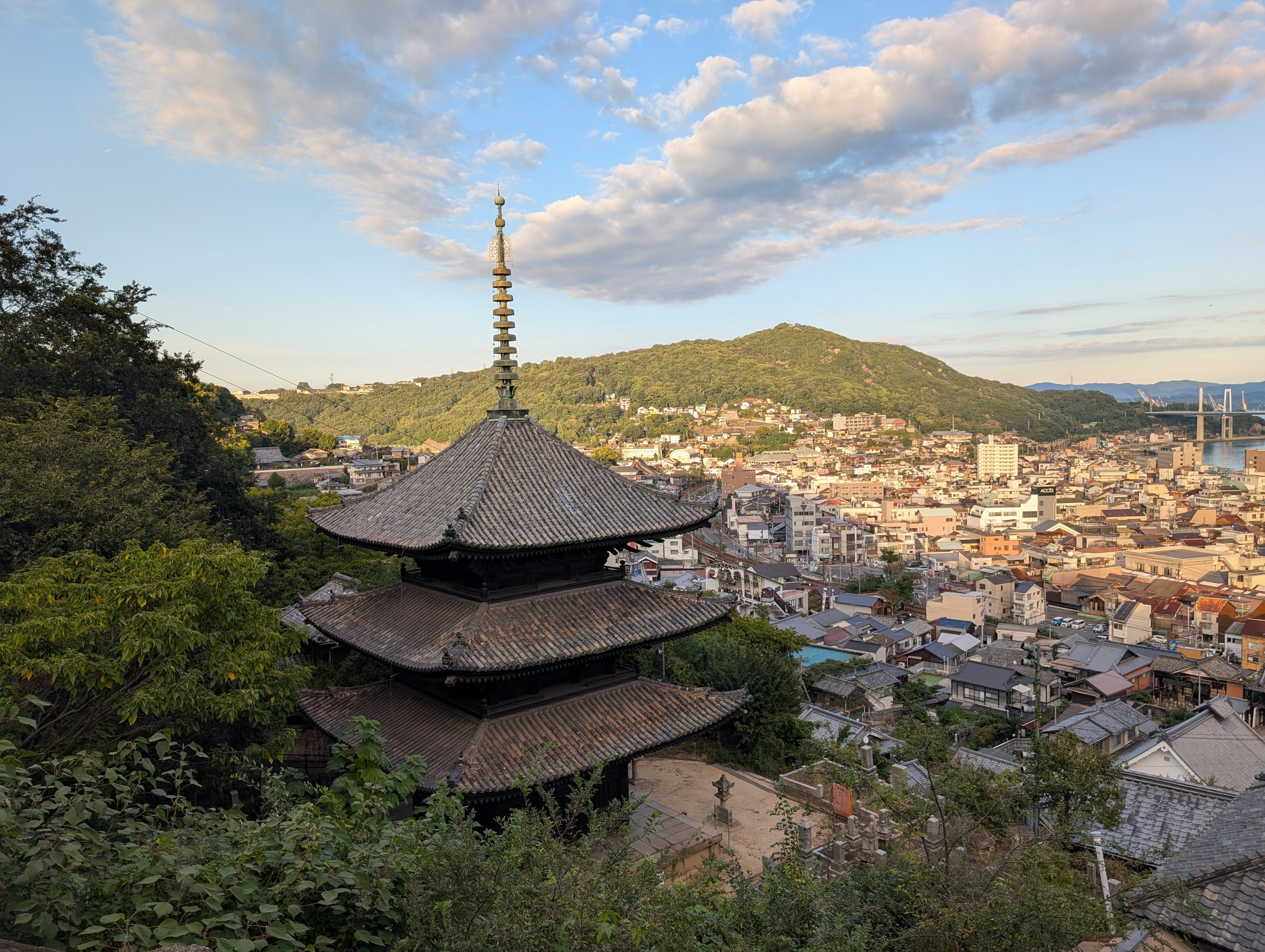 夕方の光の中の三重塔と、その向こうの尾道の町