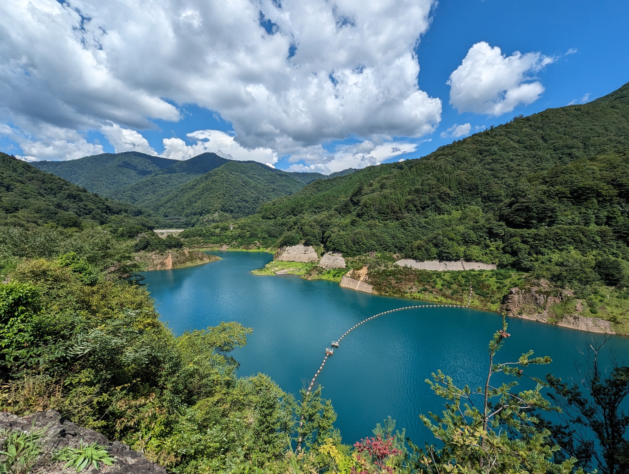 白い雲と緑の山、湖に架かる白い橋と青い湖面