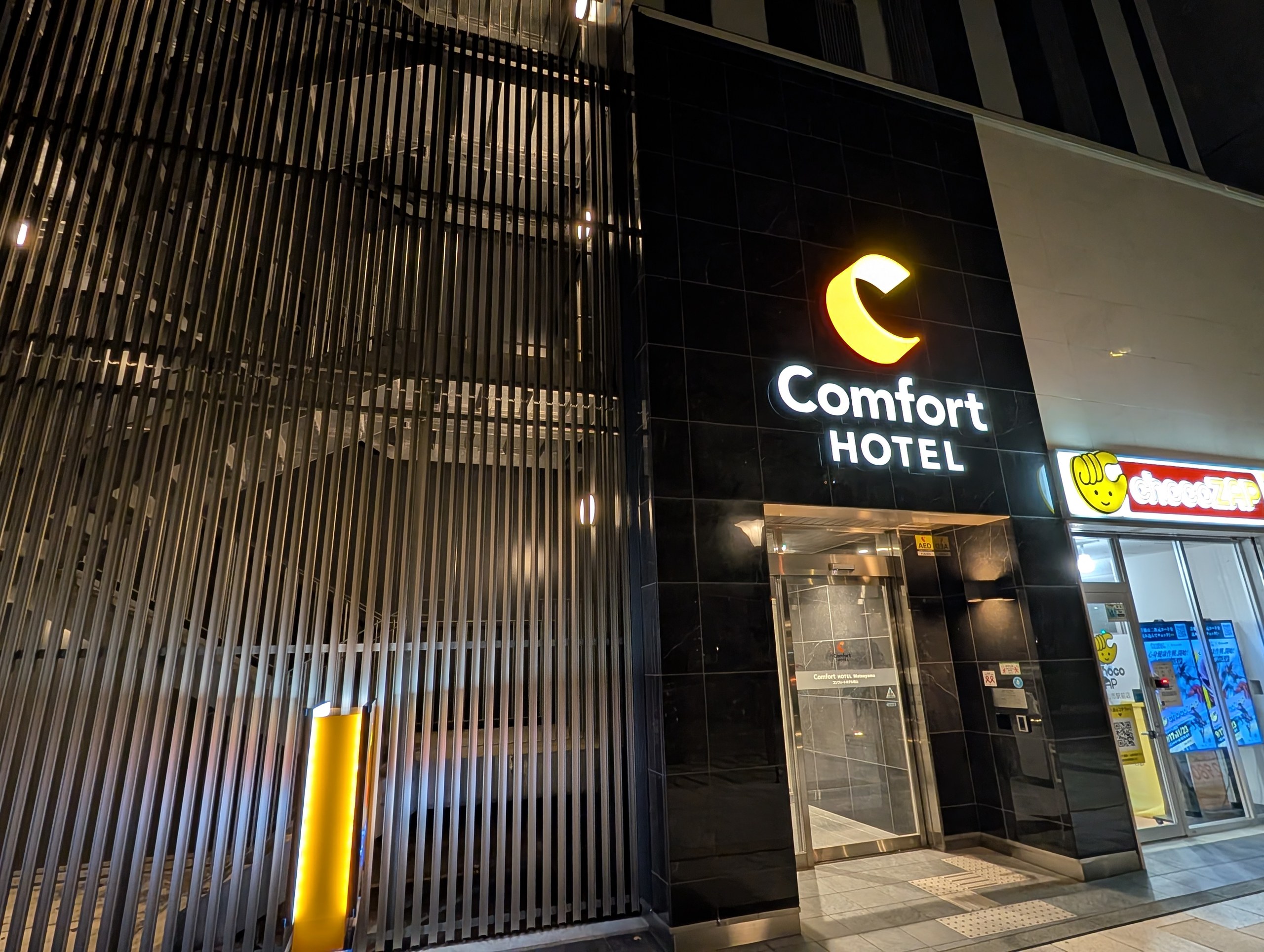 夜に光る「Comfort HOTEL」の看板と、ホテルの入口