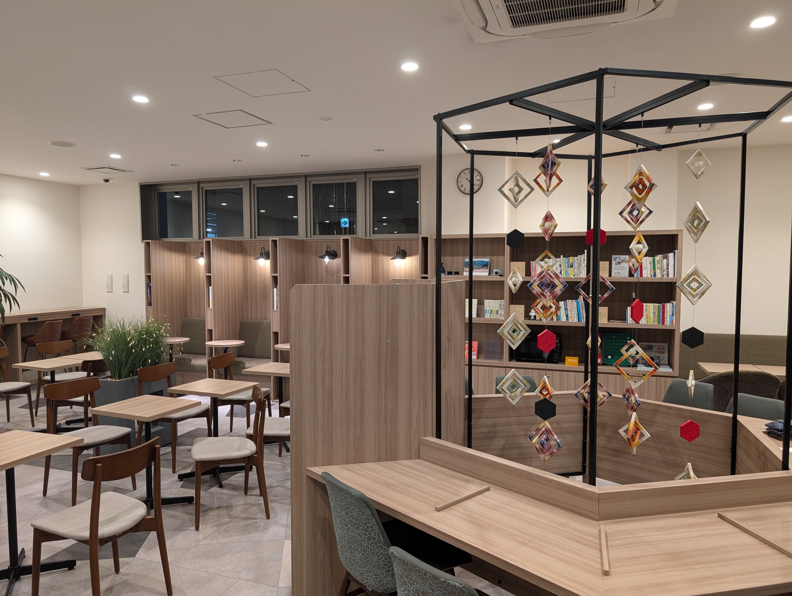 本棚と木のテーブルが並ぶ、夜のライブラリーカフェ