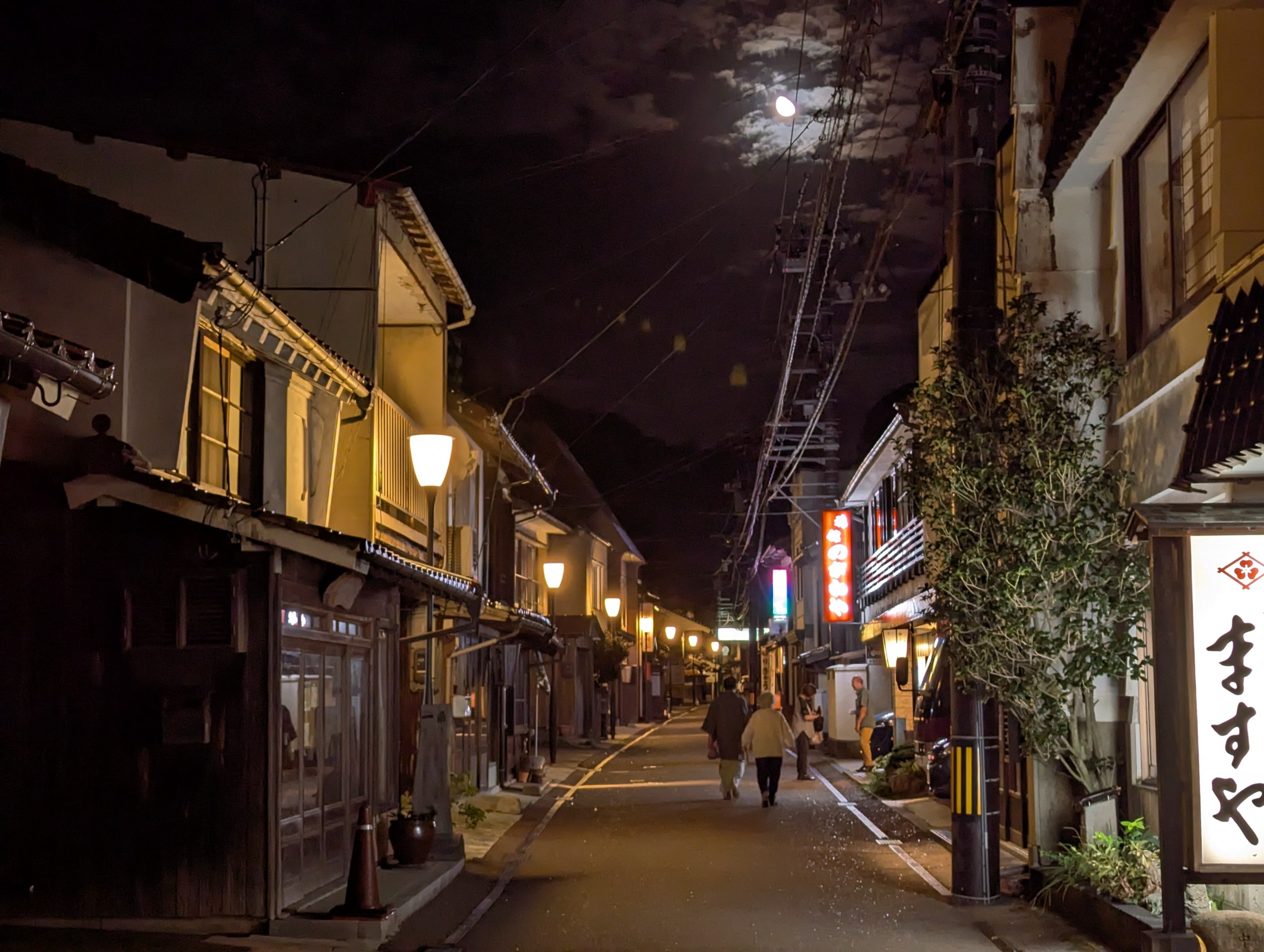 街灯が灯る夜の温泉津温泉の通りと、木造の建物が並ぶ町並み