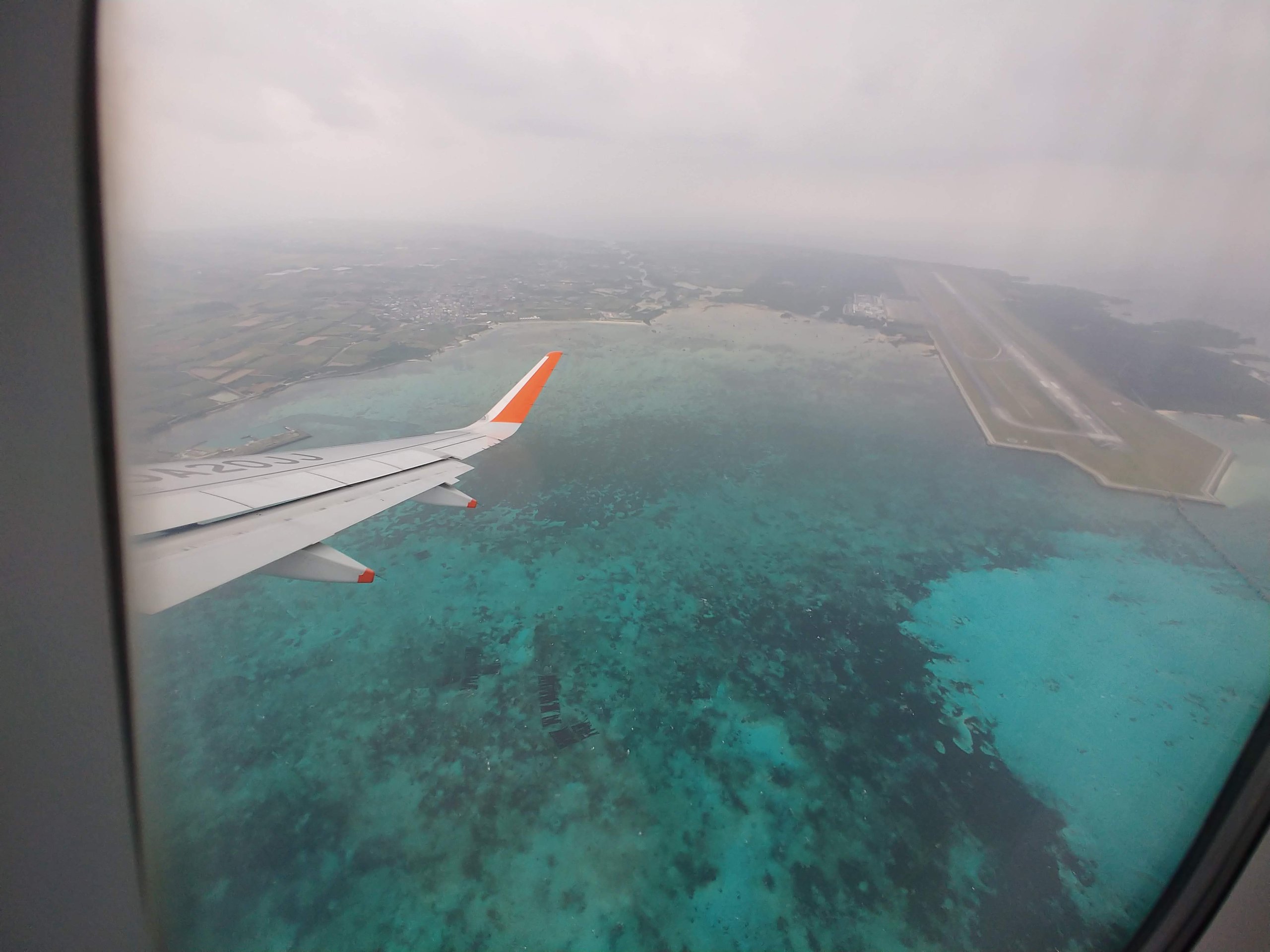 離陸した飛行機の窓から見たサンゴ礁の海と下地島の滑走路