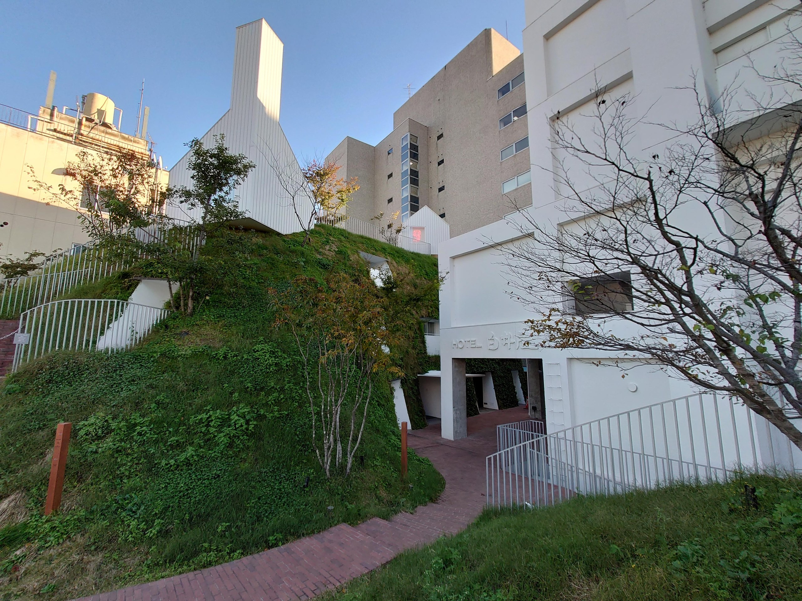 丘の斜面に沿って続く小道と、白い建物の外階段