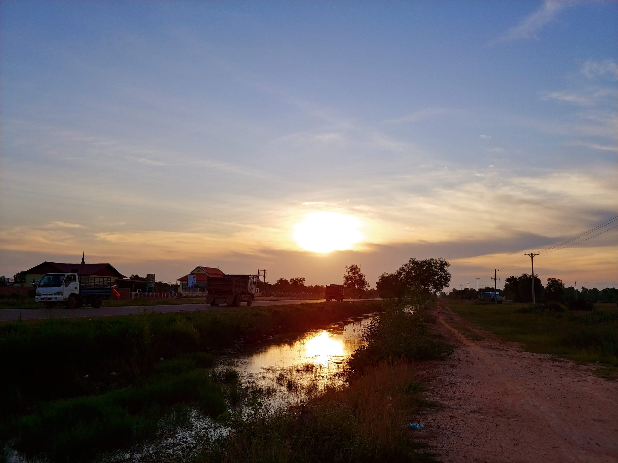 道ばたから見た夕日と水路