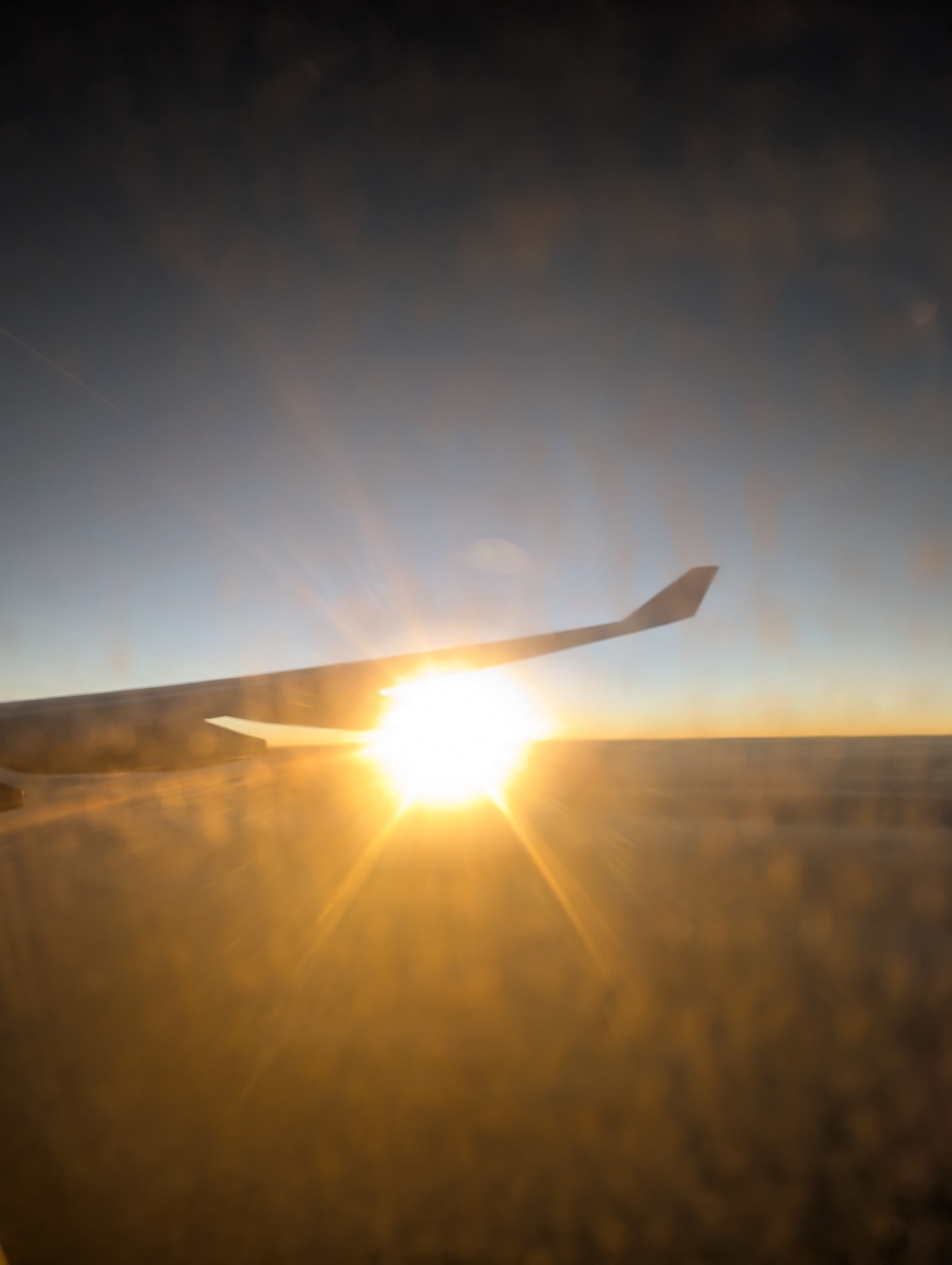 飛行機の窓から見た、翼の向こうの初日の出