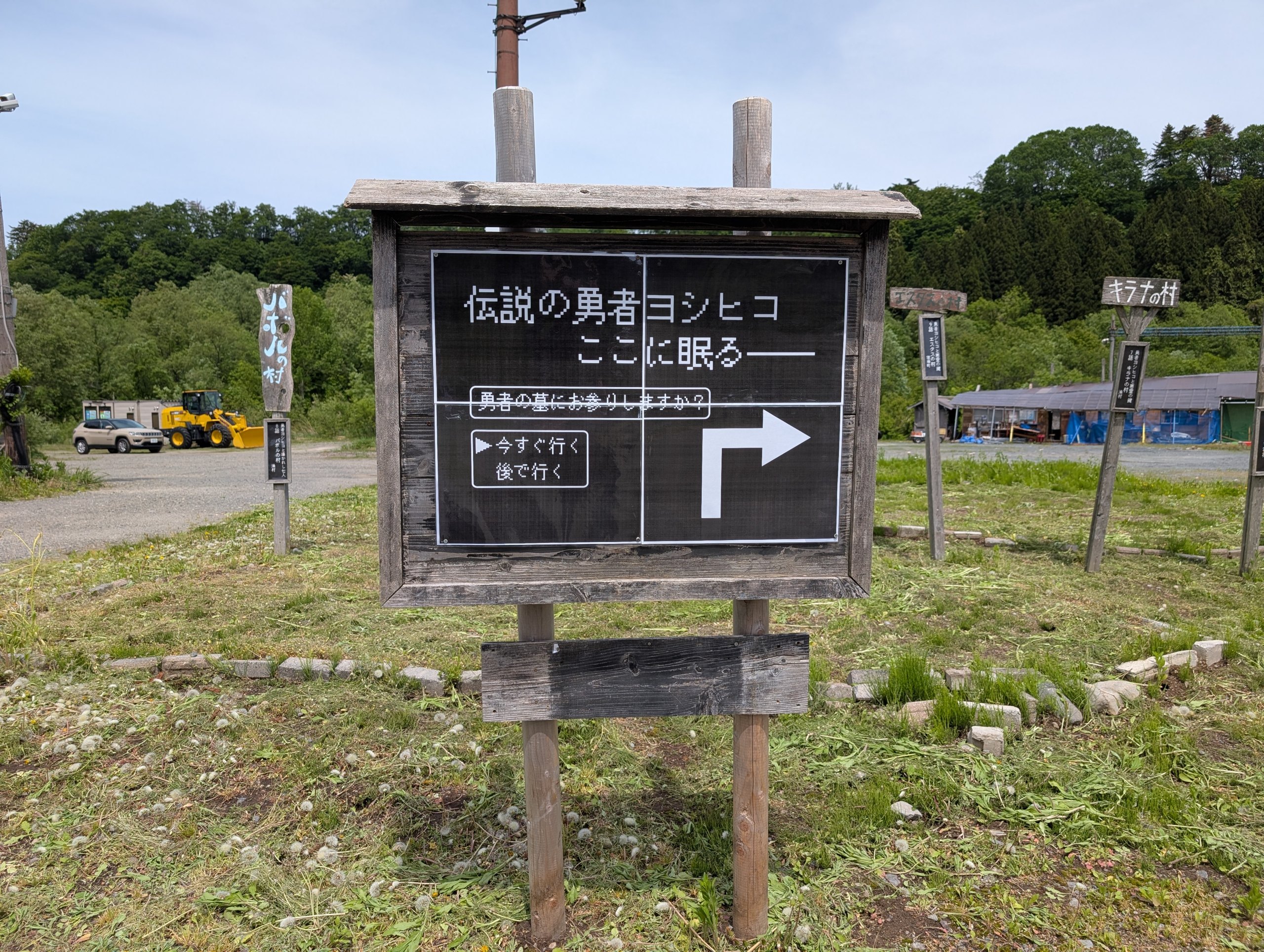 「伝説の勇者ヨシヒコ ここに眠る」と書かれた、ゲーム画面のような看板