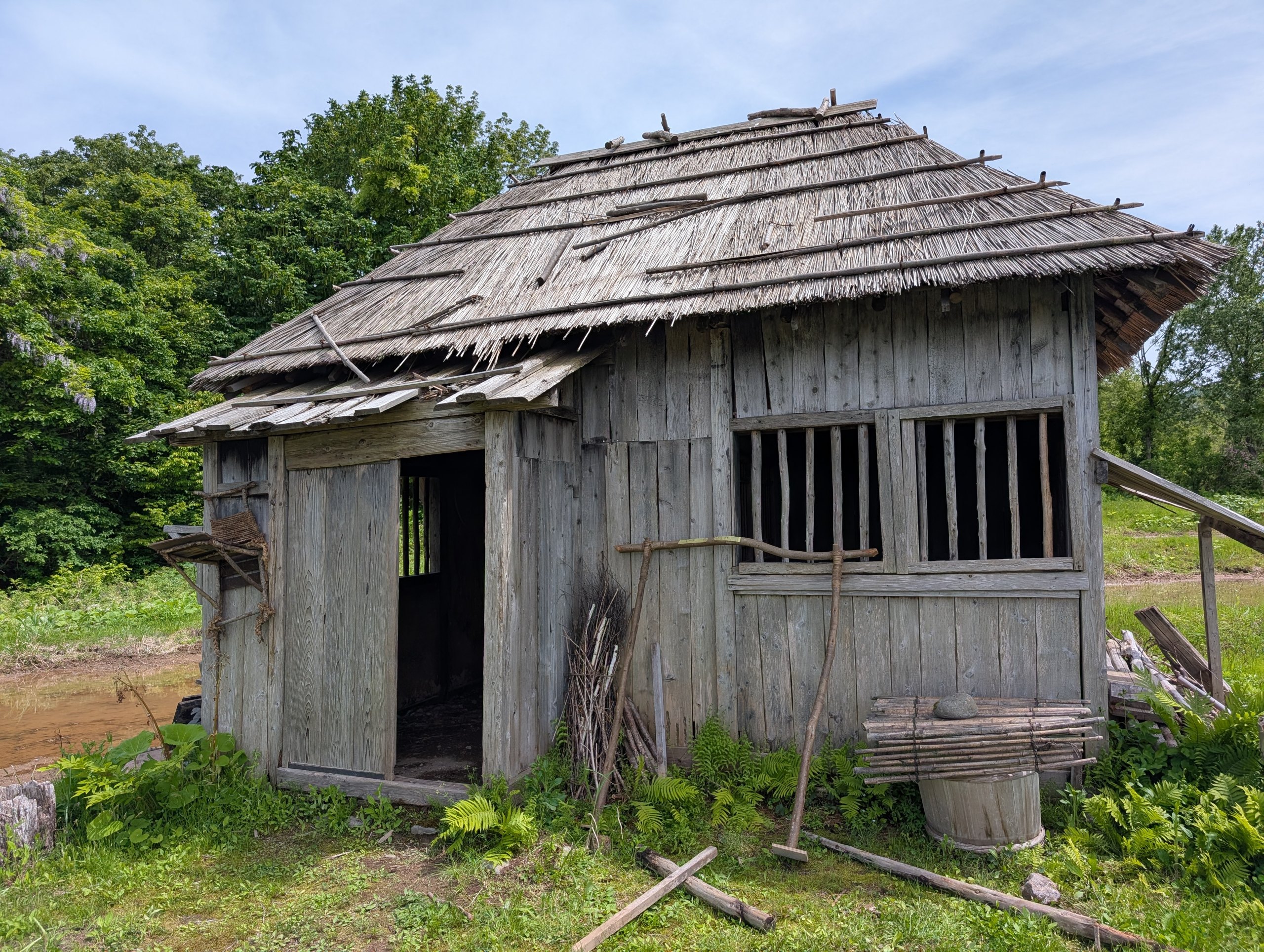 板壁が傷んだ、かやぶき屋根の小屋