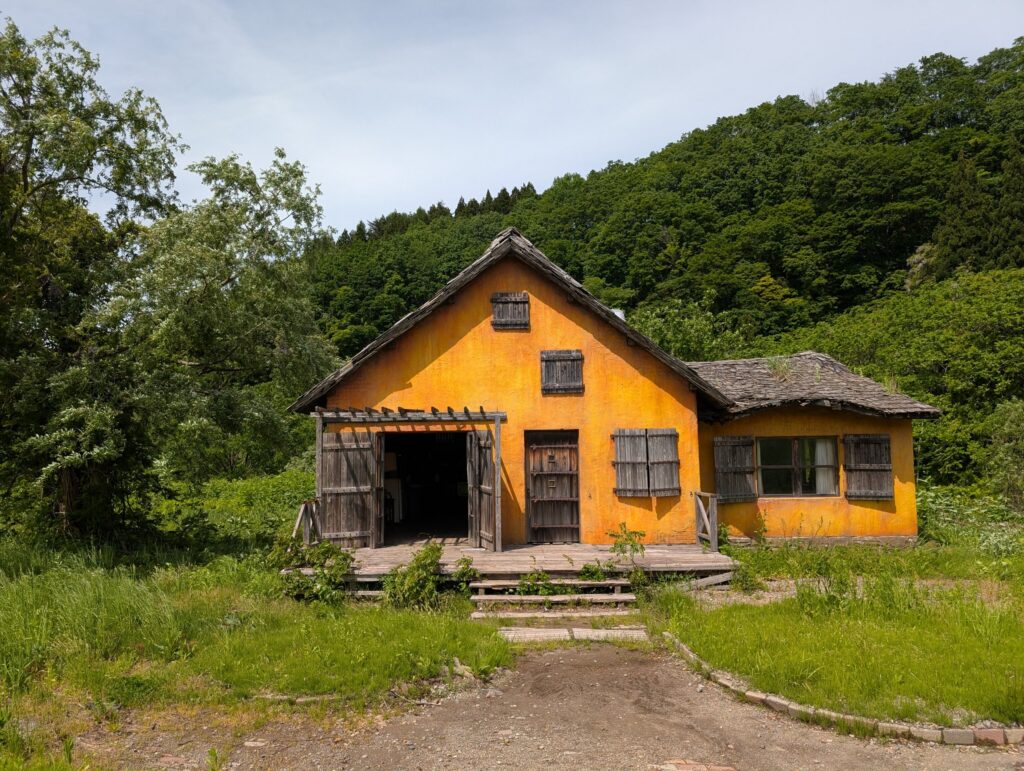 森を背にして建つ、黄色い壁の洋風の家