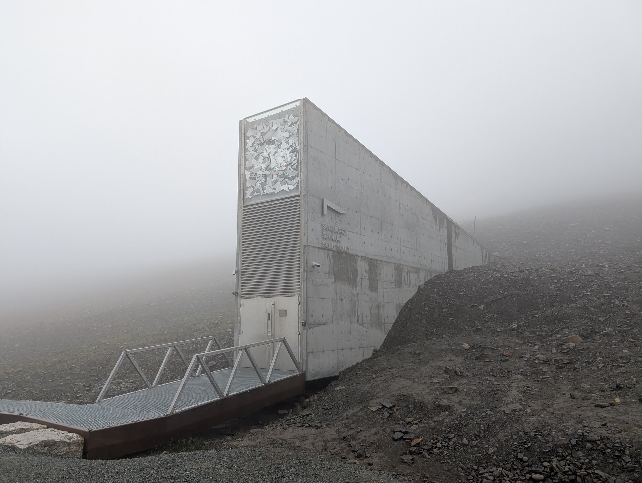 霧の中、山の斜面から突き出したコンクリートの入口の建物