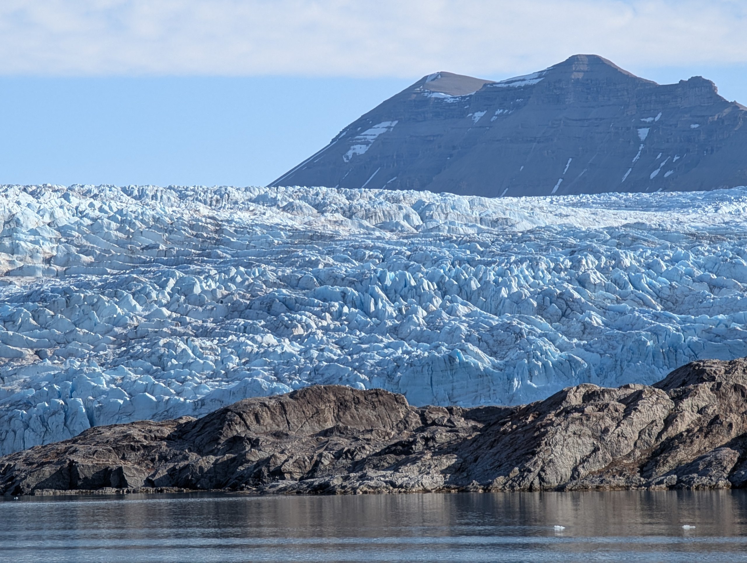 青白く輝くノルデンショルド氷河の壁と、後ろの山