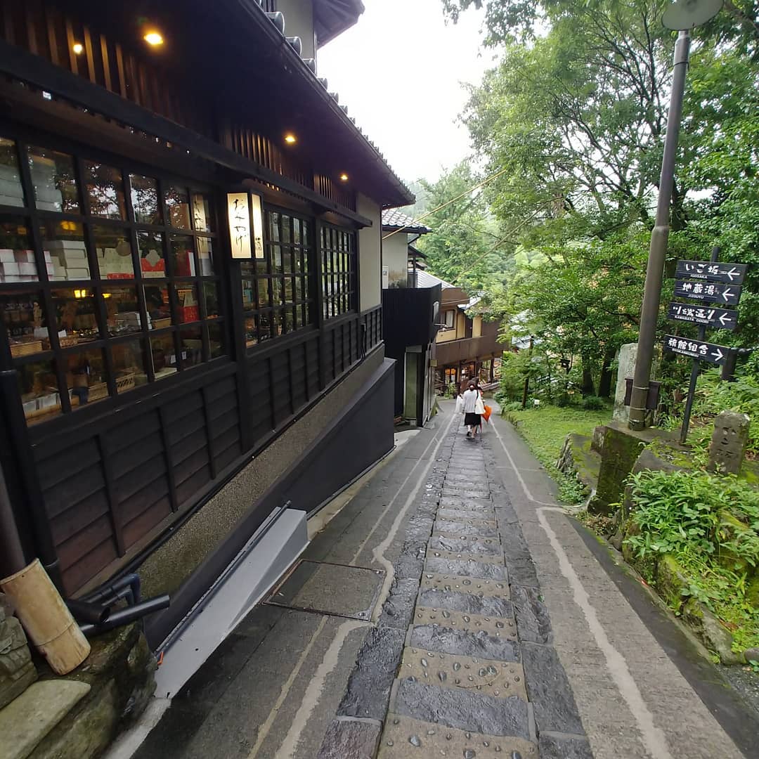 雨にぬれた黒川温泉の石畳の路地と木造の店