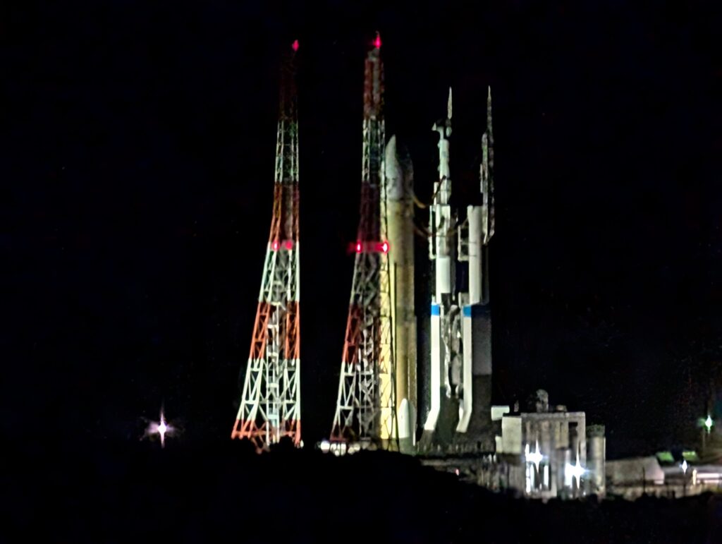 夜の発射台にライトアップされて立つH3ロケットと、赤白の塔