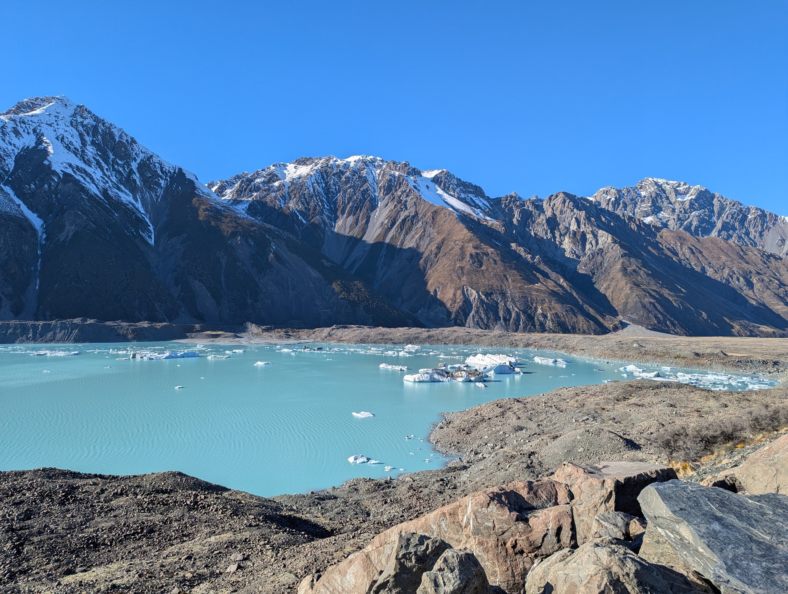雪山に囲まれた水色のタスマン湖。湖面に白い氷山がいくつも浮かんでいる