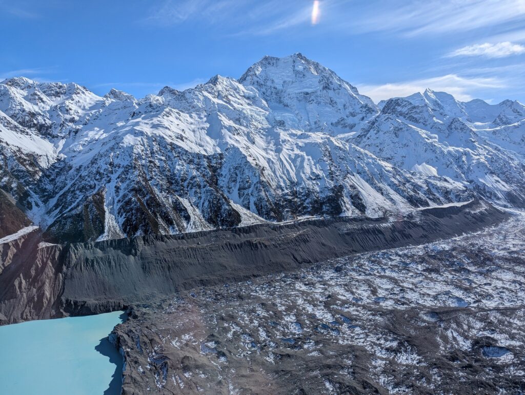 上空から見た、雪山の間を流れるタスマン氷河。手前にタスマン湖の水色が少し見える