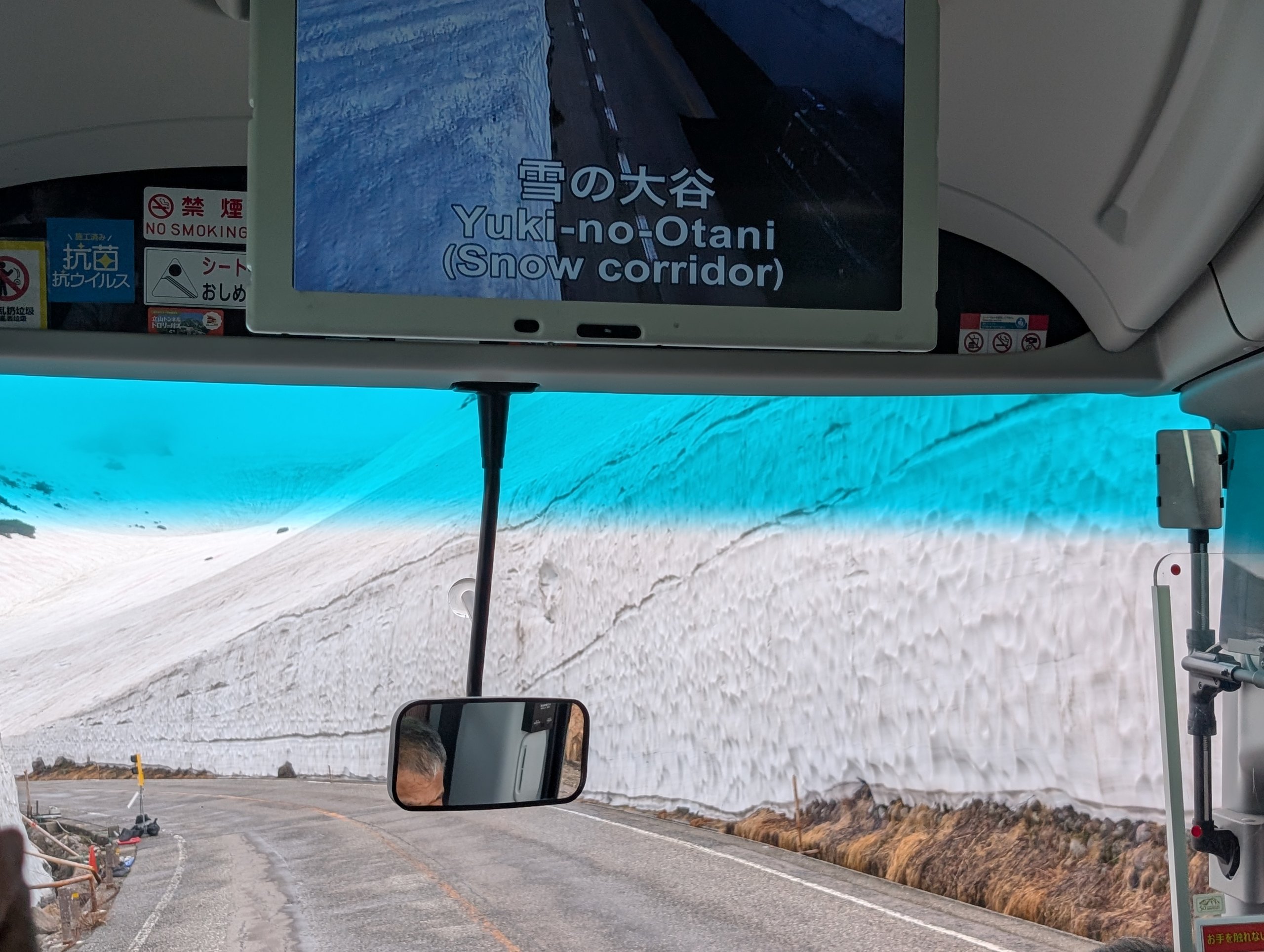 雪の壁のあいだを走るバスの車内と、「雪の大谷」と出たモニター