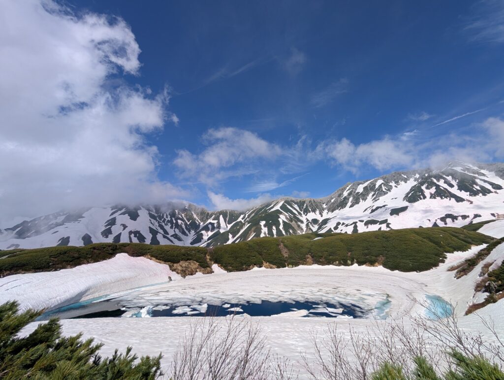 青空の下、雪の山と氷の浮かぶみくりが池