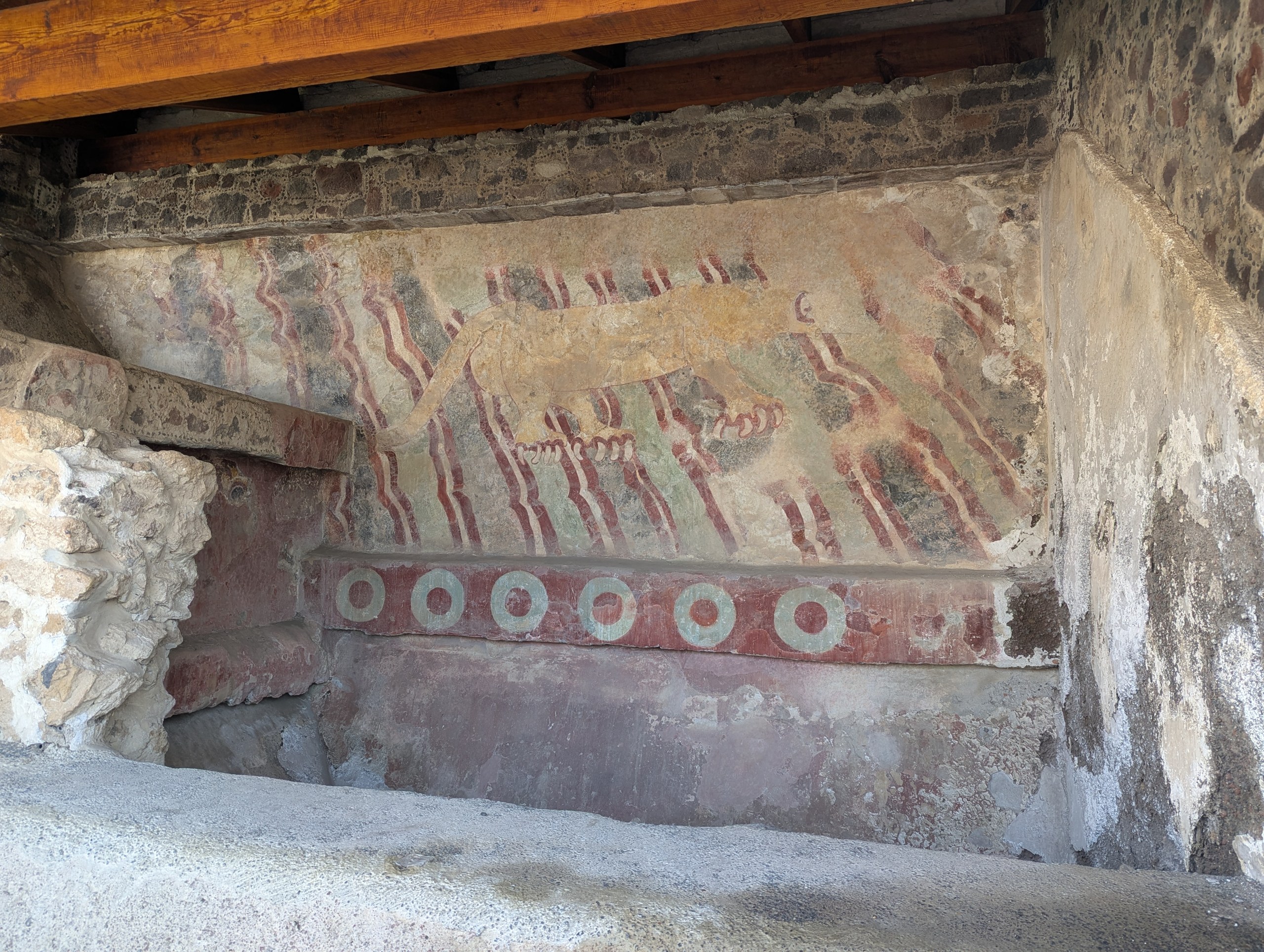 屋根の下の壁に残る、赤い地にうねる線と丸い模様の壁画