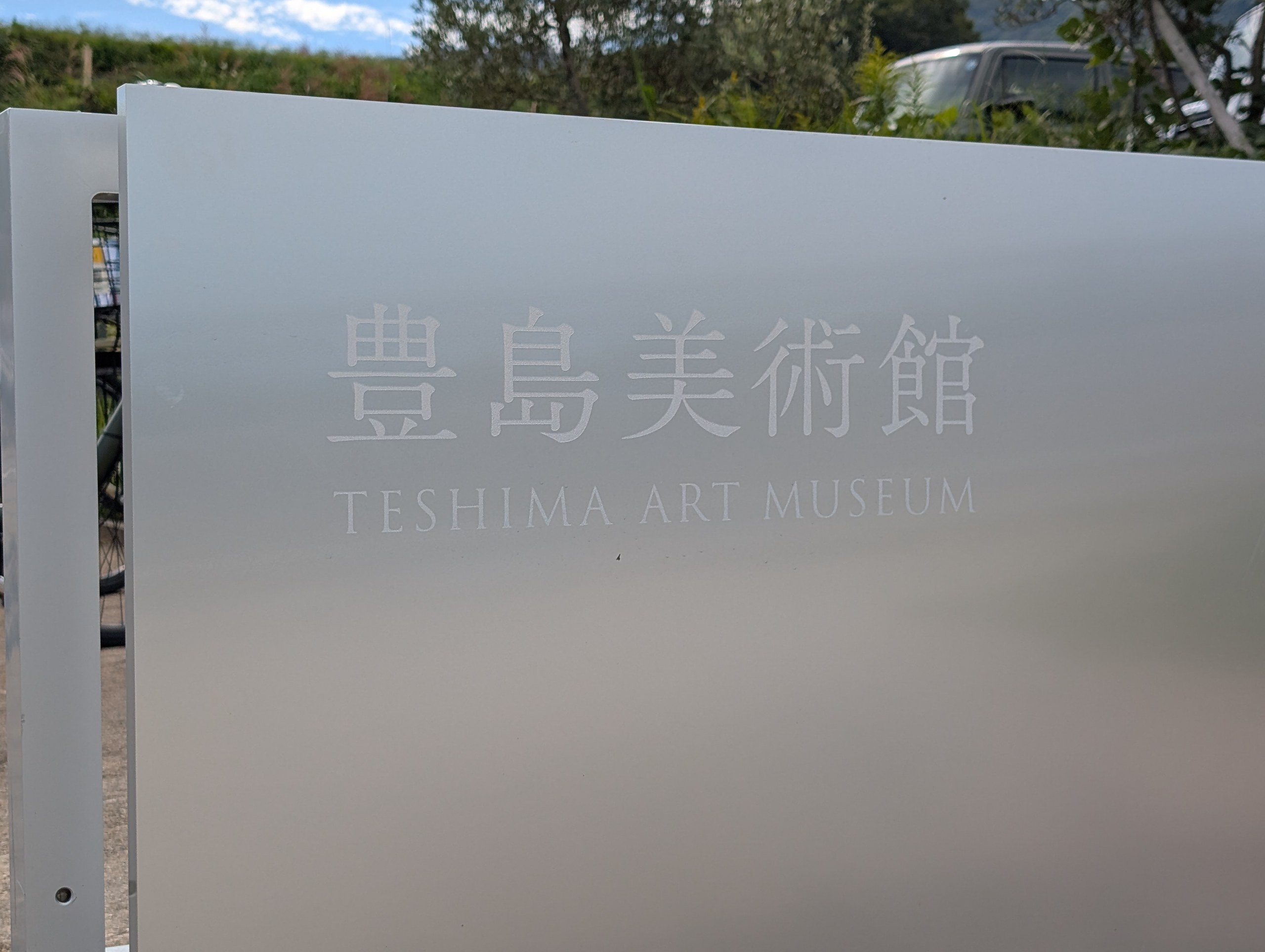 すりガラスのような板に書かれた「豊島美術館 TESHIMA ART MUSEUM」
