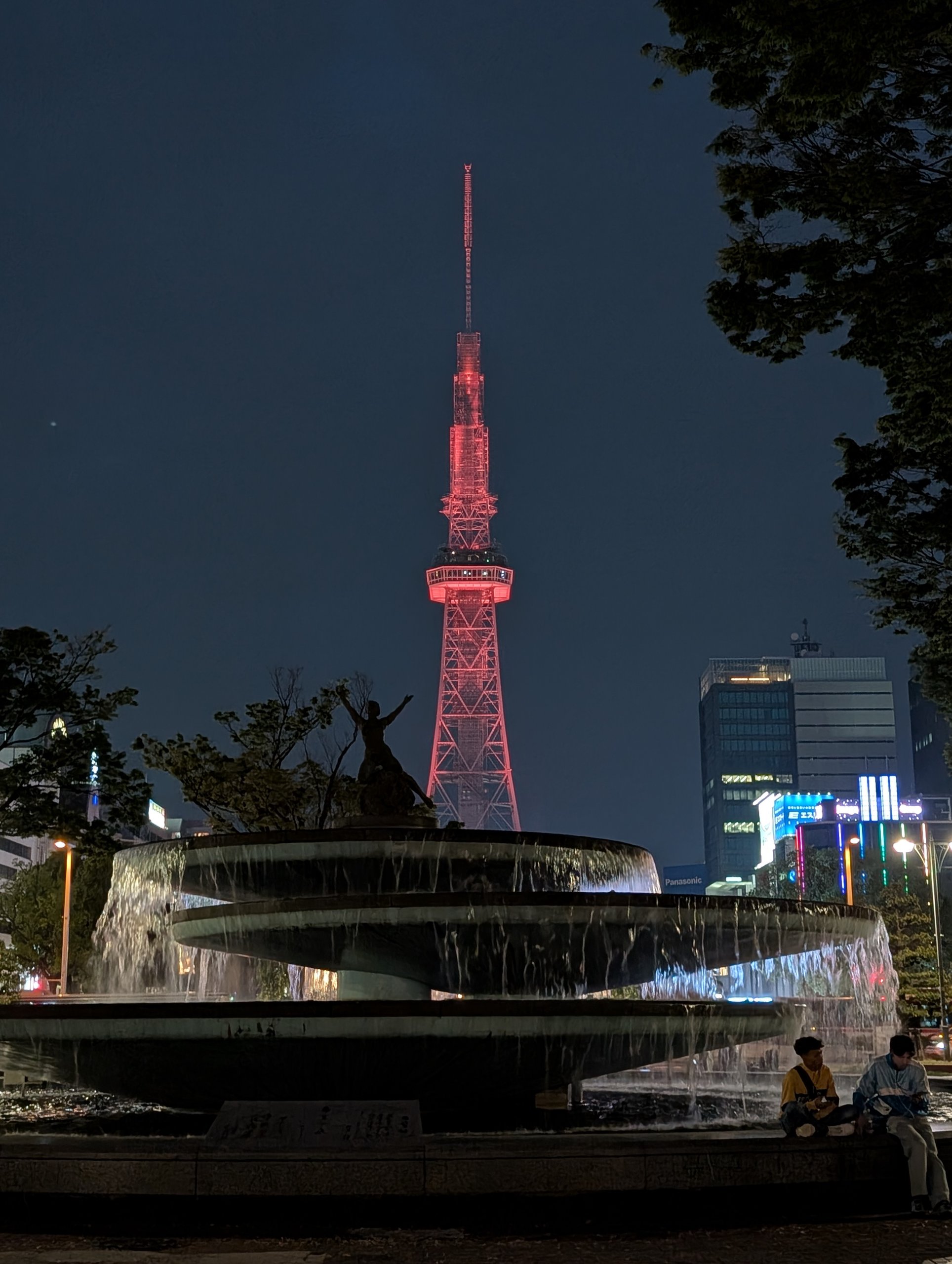 赤くライトアップされた夜の中部電力 MIRAI TOWERと、手前の噴水