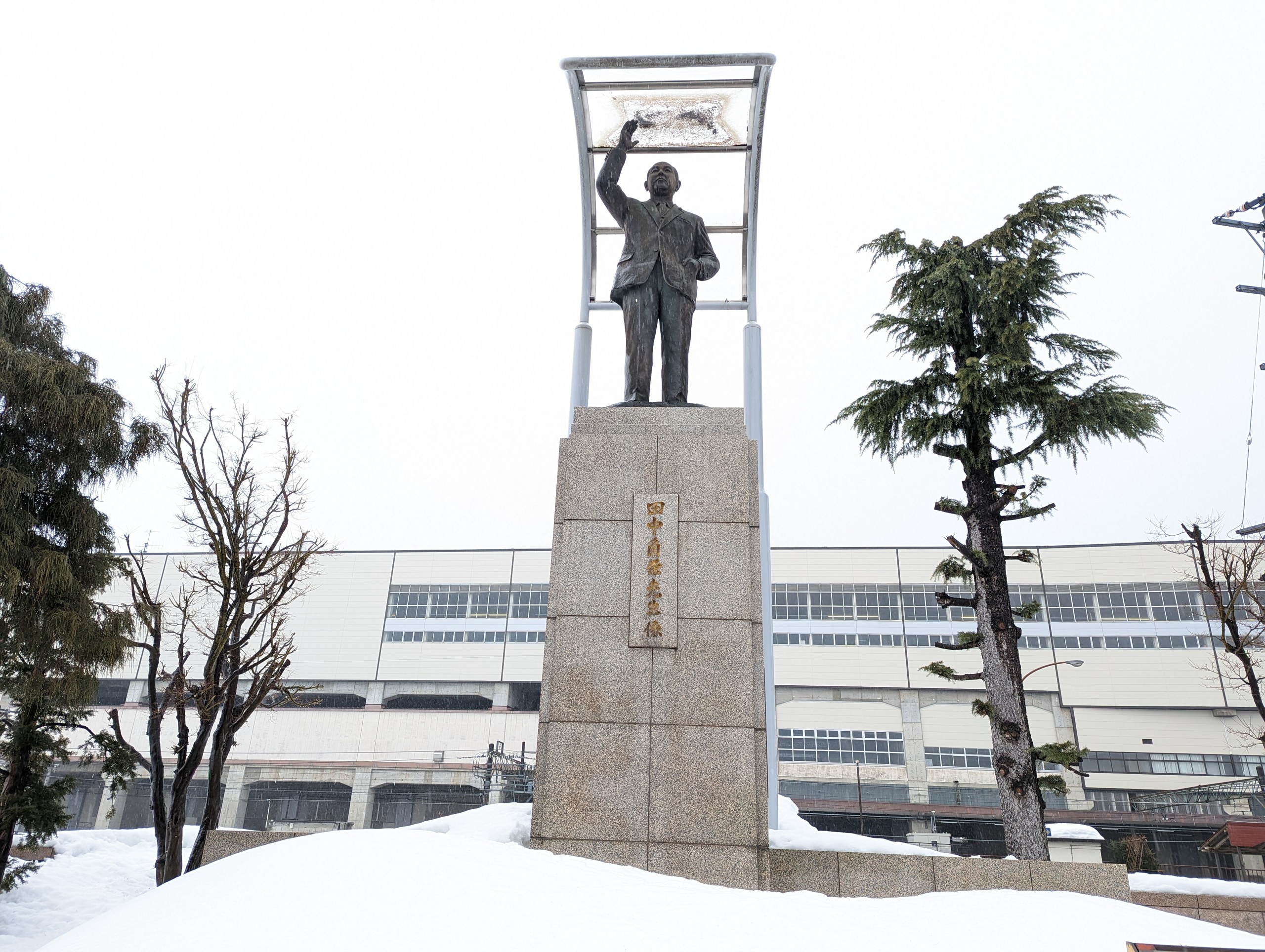 雪の中の台座に立つ、浦佐駅前の田中角栄の銅像
