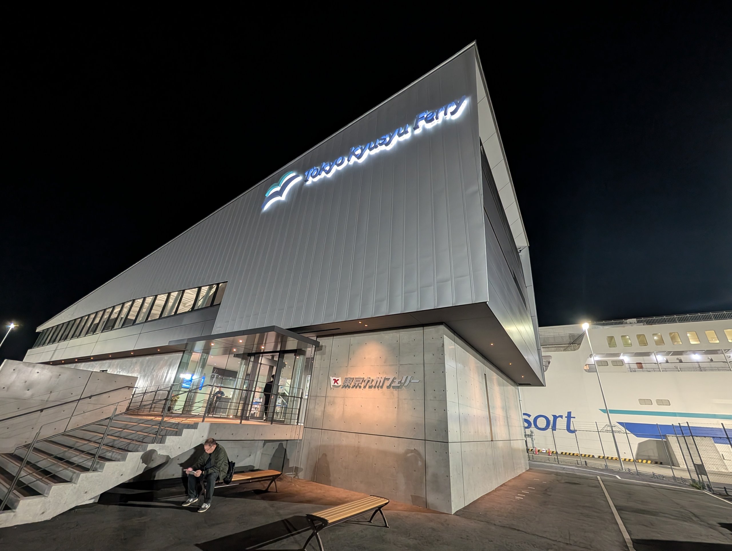 夜の横須賀のフェリーターミナル。ガラス張りの建物と、その奥の船
