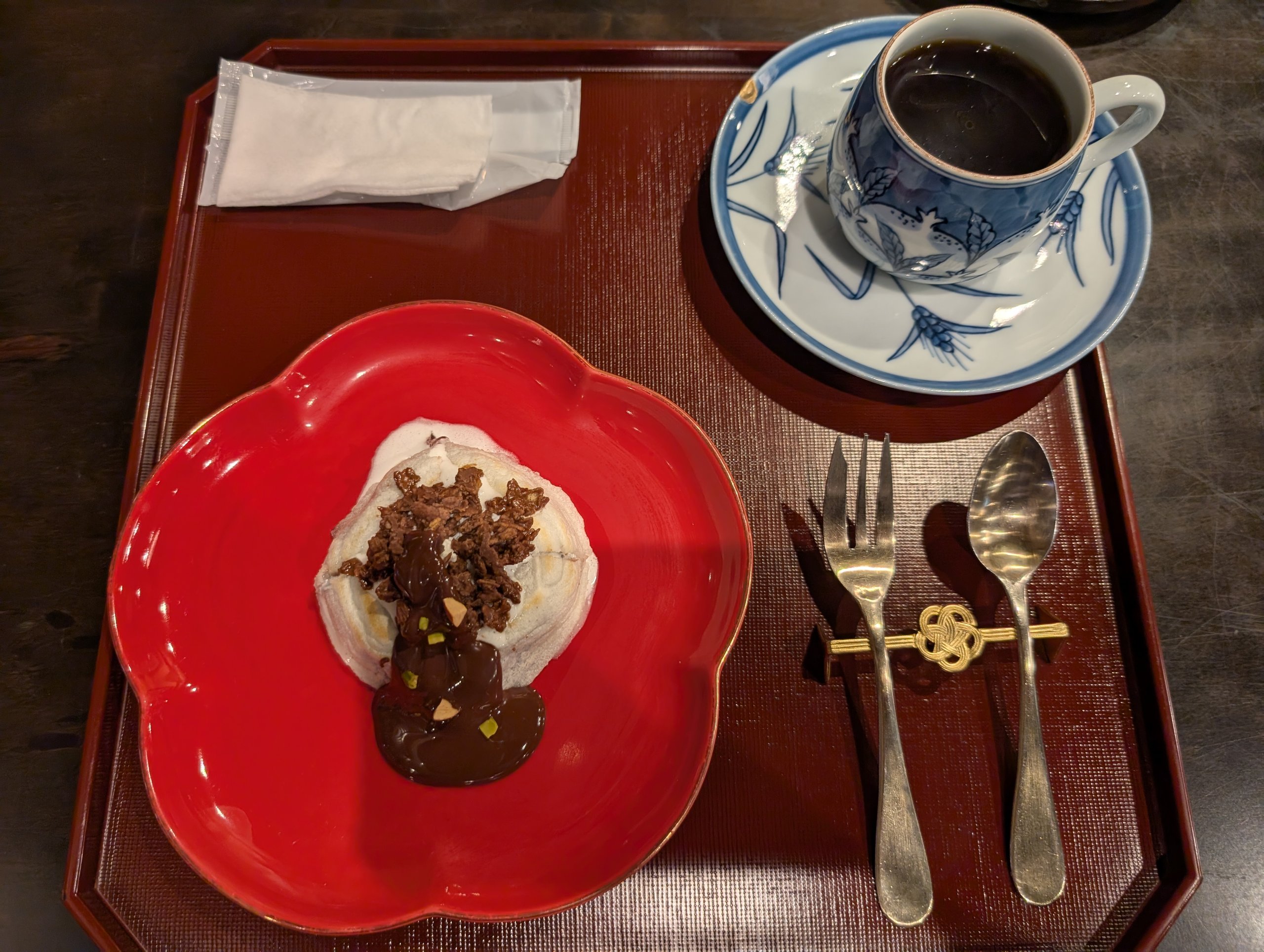 赤い皿にのったチョコレートのデザートと、青い模様のカップのコーヒー