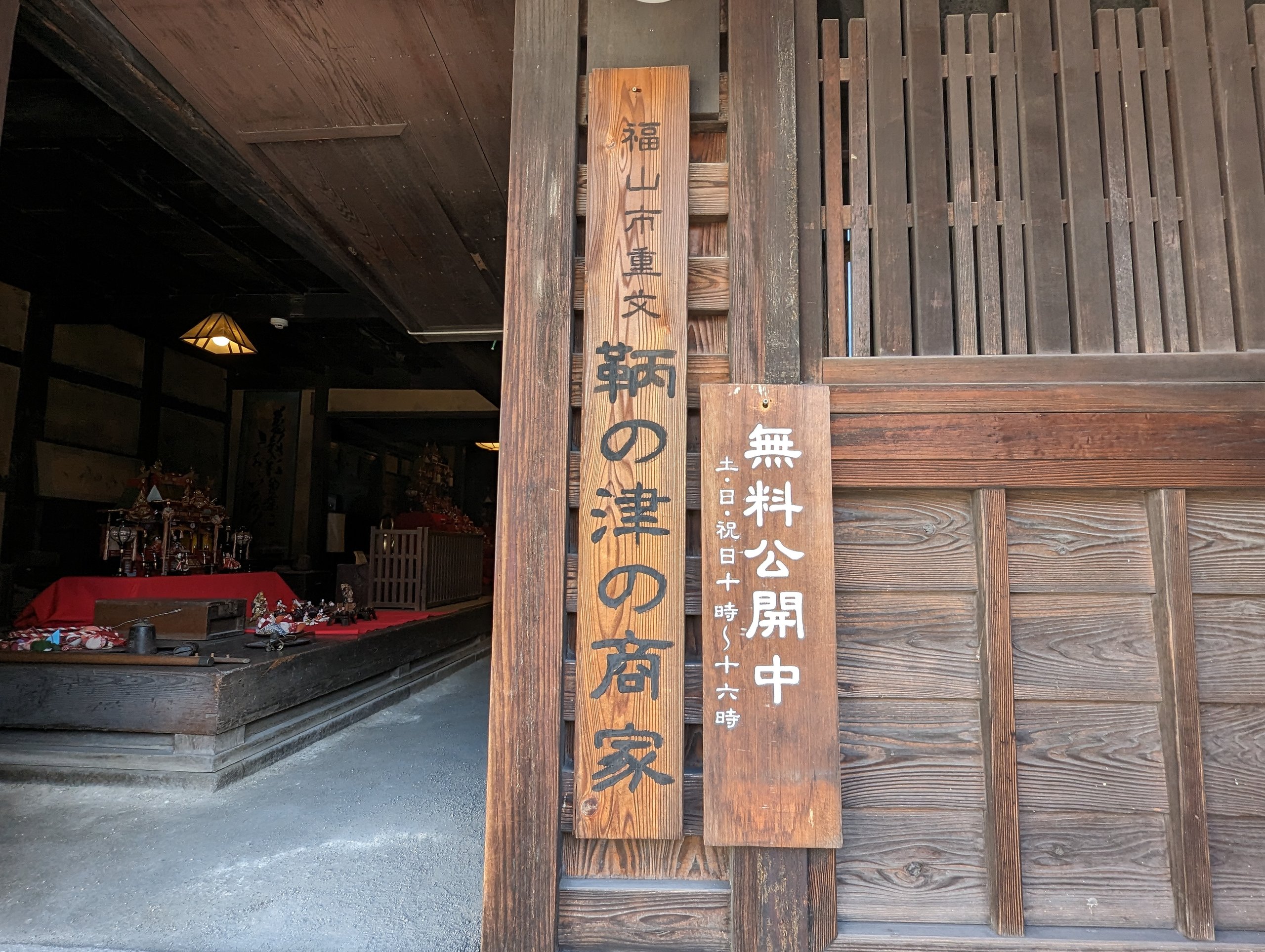 「鞆の津の商家」の木の看板が掛かる、町家の入口